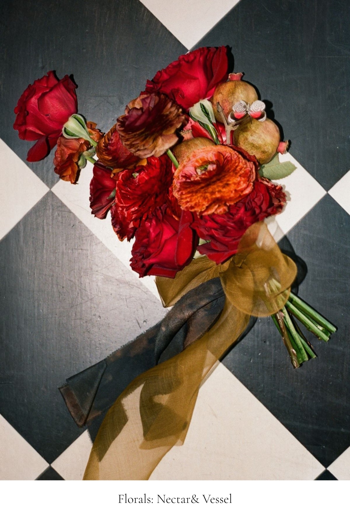 Bouquet of red and orange flowers by Nectar & Vessel with a silk & Willow ochre ribbon on a black and white checkered background.
