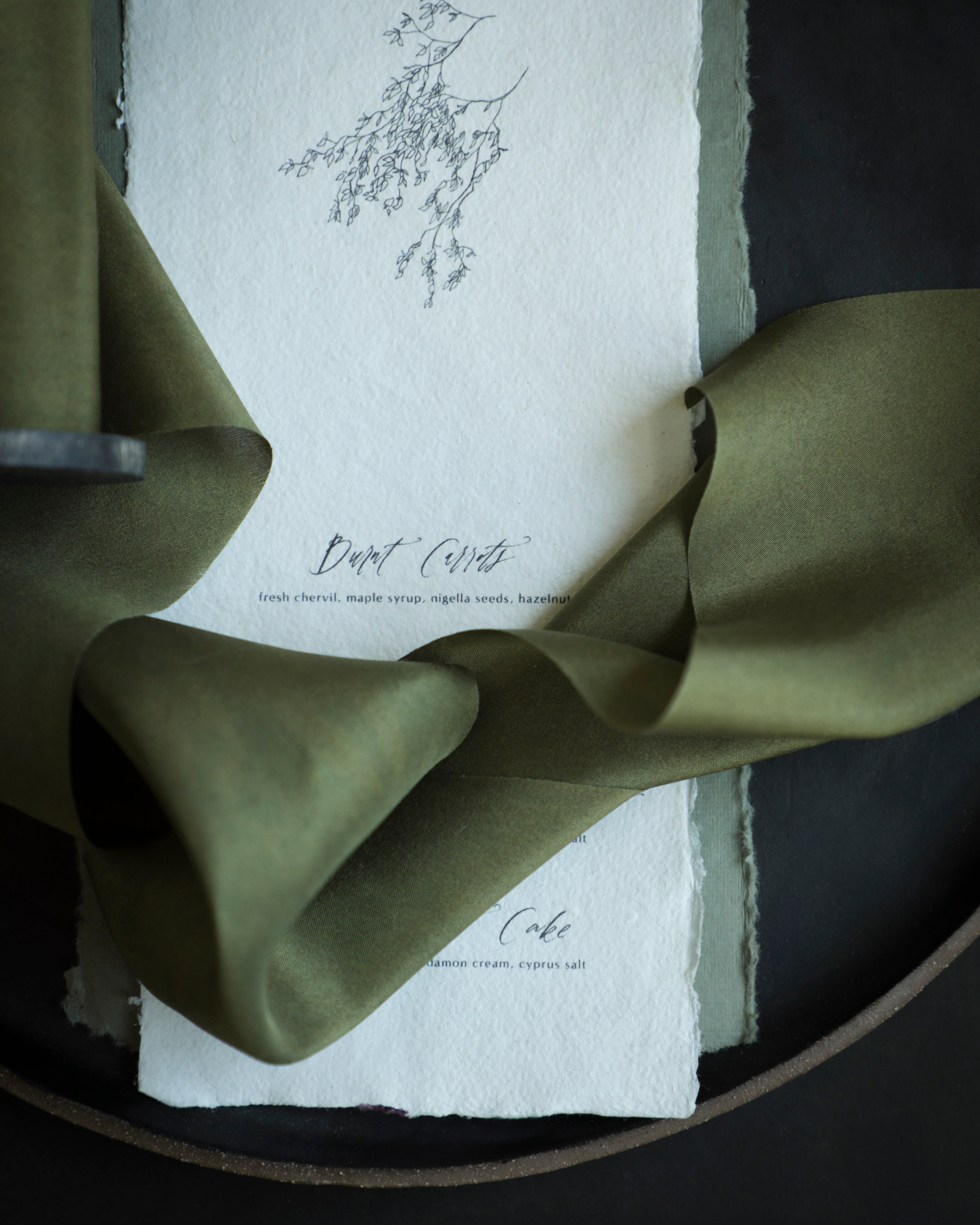 Green ribbon on a white card with text and floral design