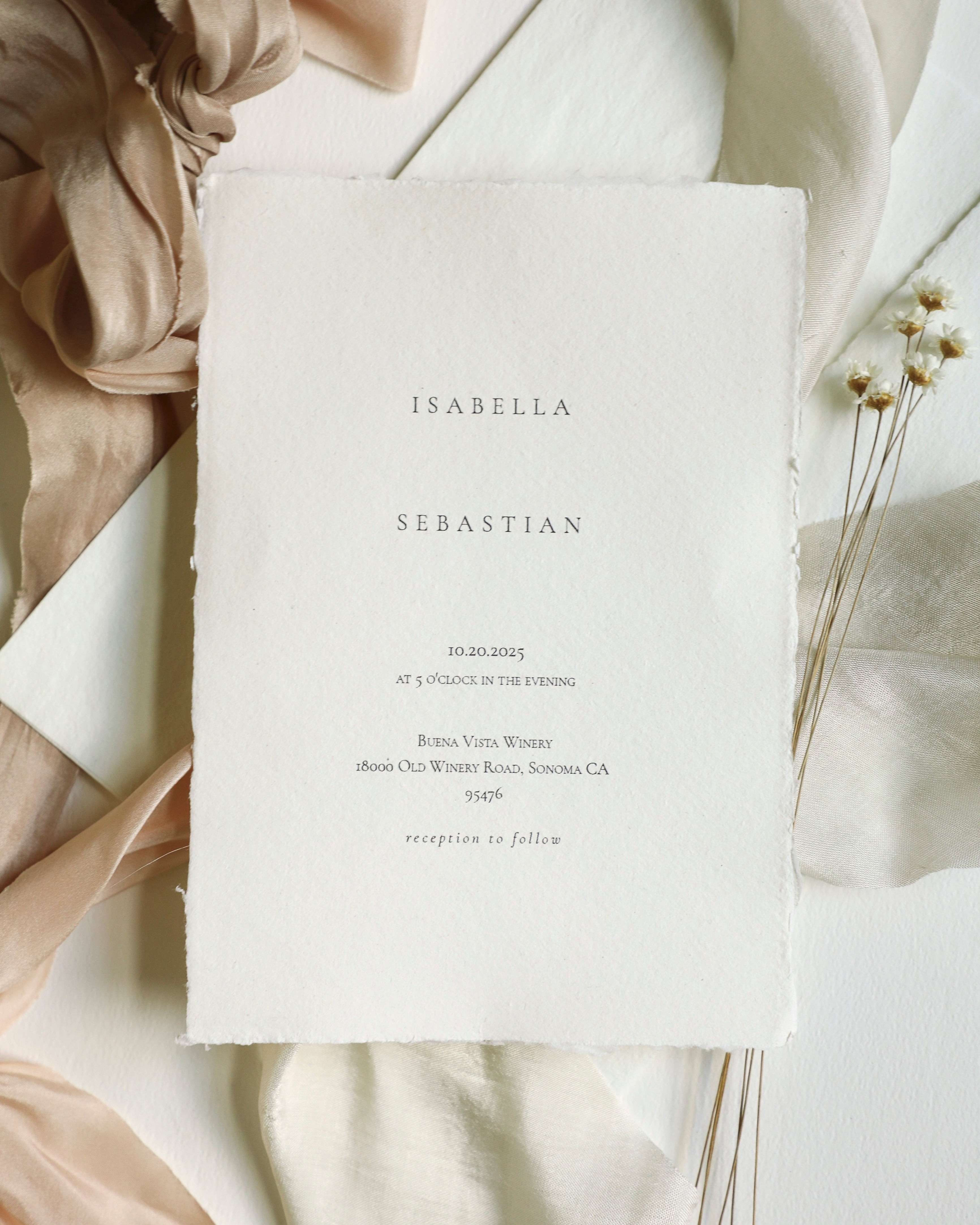 White invitation card with text on a soft beige fabric background