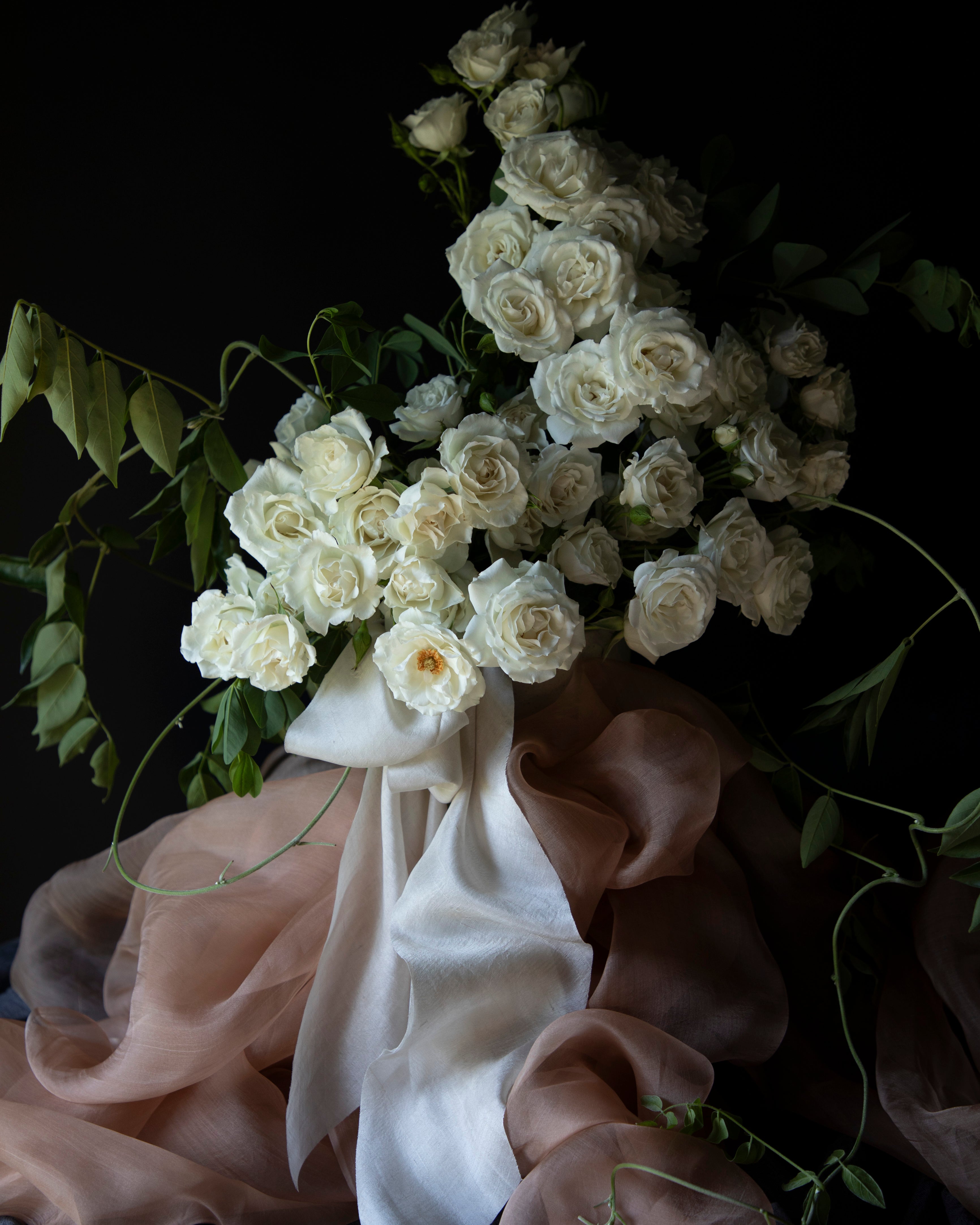 white organic silk ribbon tied on a white rose arrangement for wedding flowers