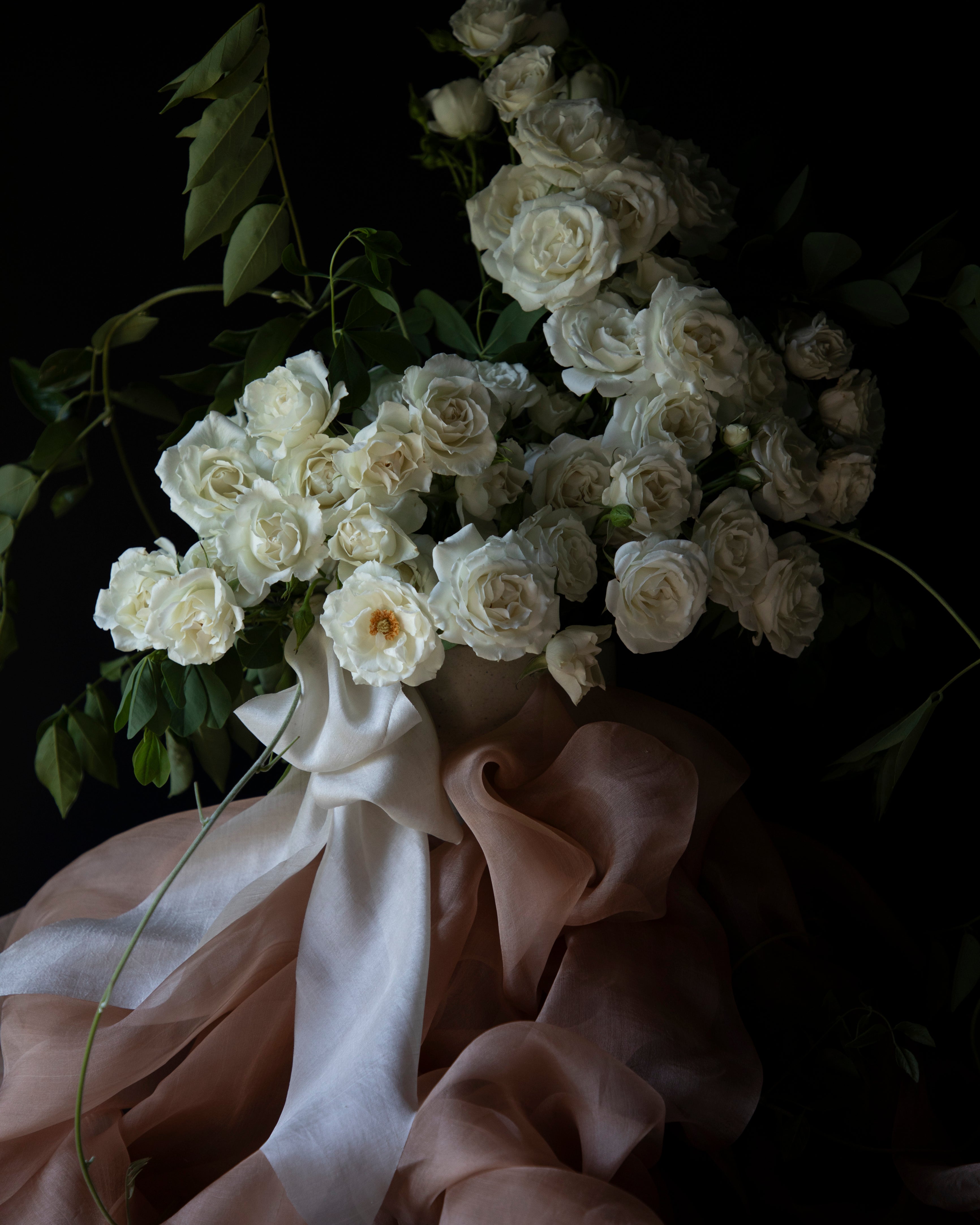 white rose floral centerpiece with peach accent and decorated with organic silk ribbon