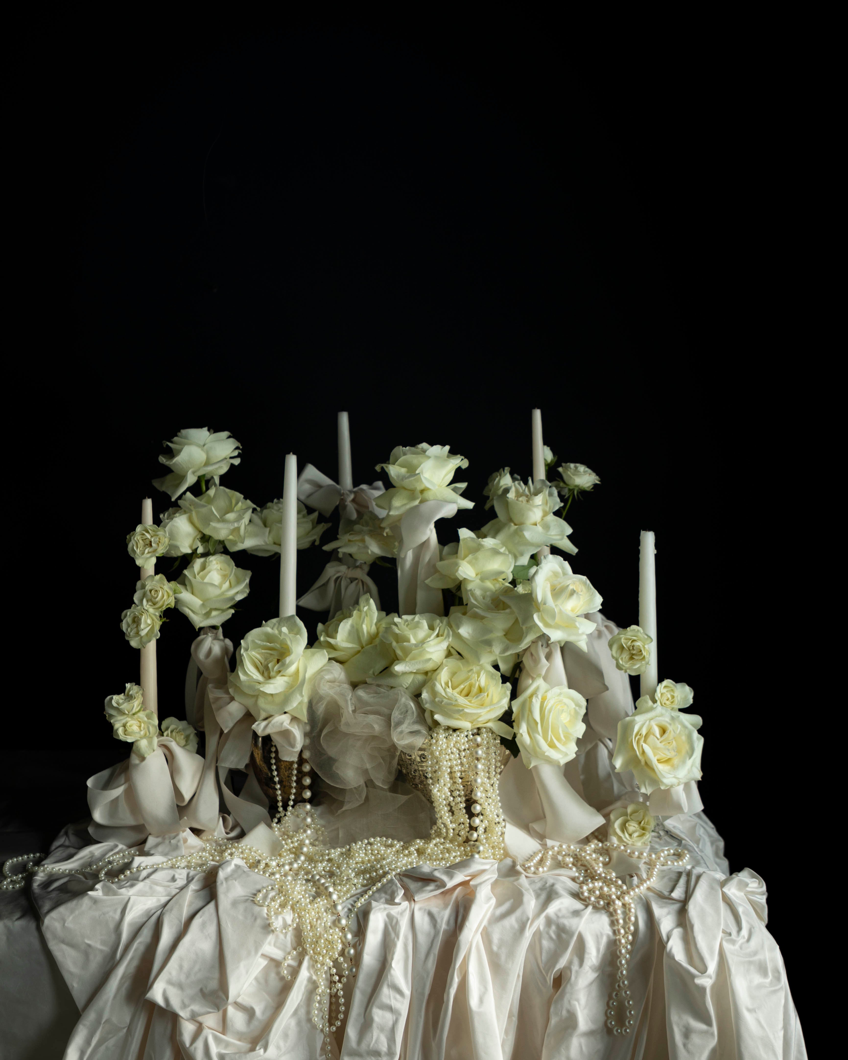 Decorative cake with white flowers and candles on a dark background