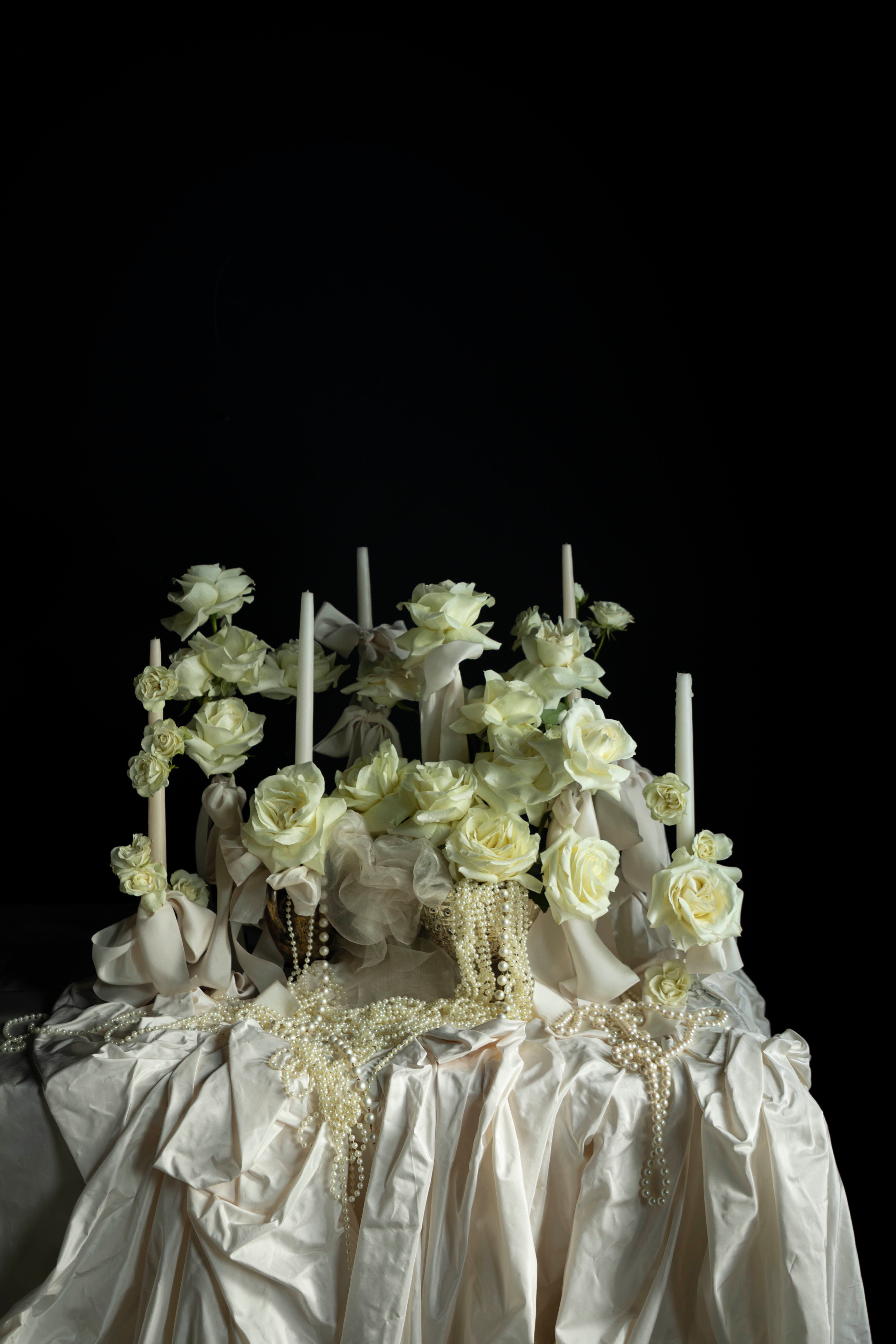 Decorative cake with white flowers and candles on a dark background