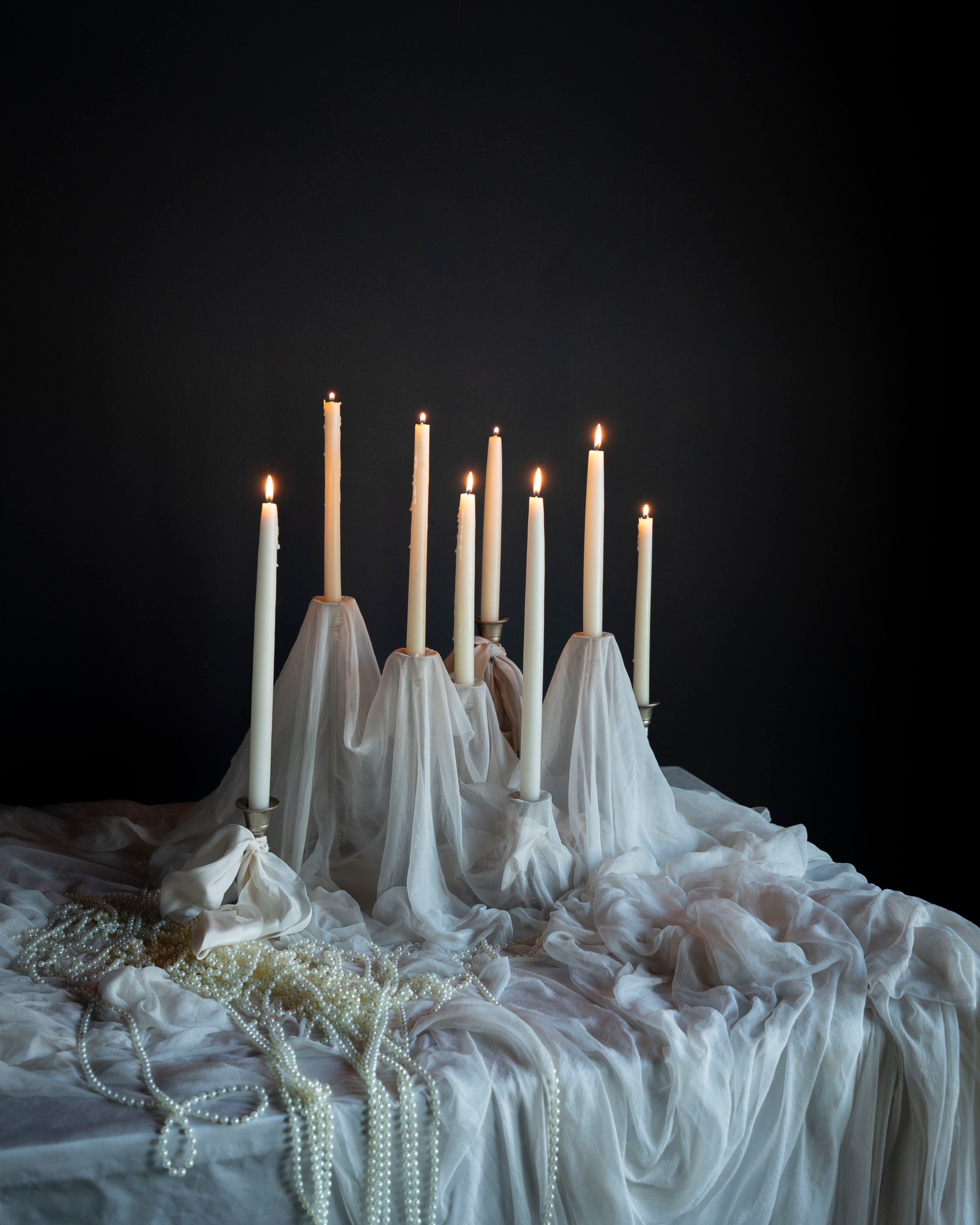Candle holder with lit candles on a draped surface against a dark background