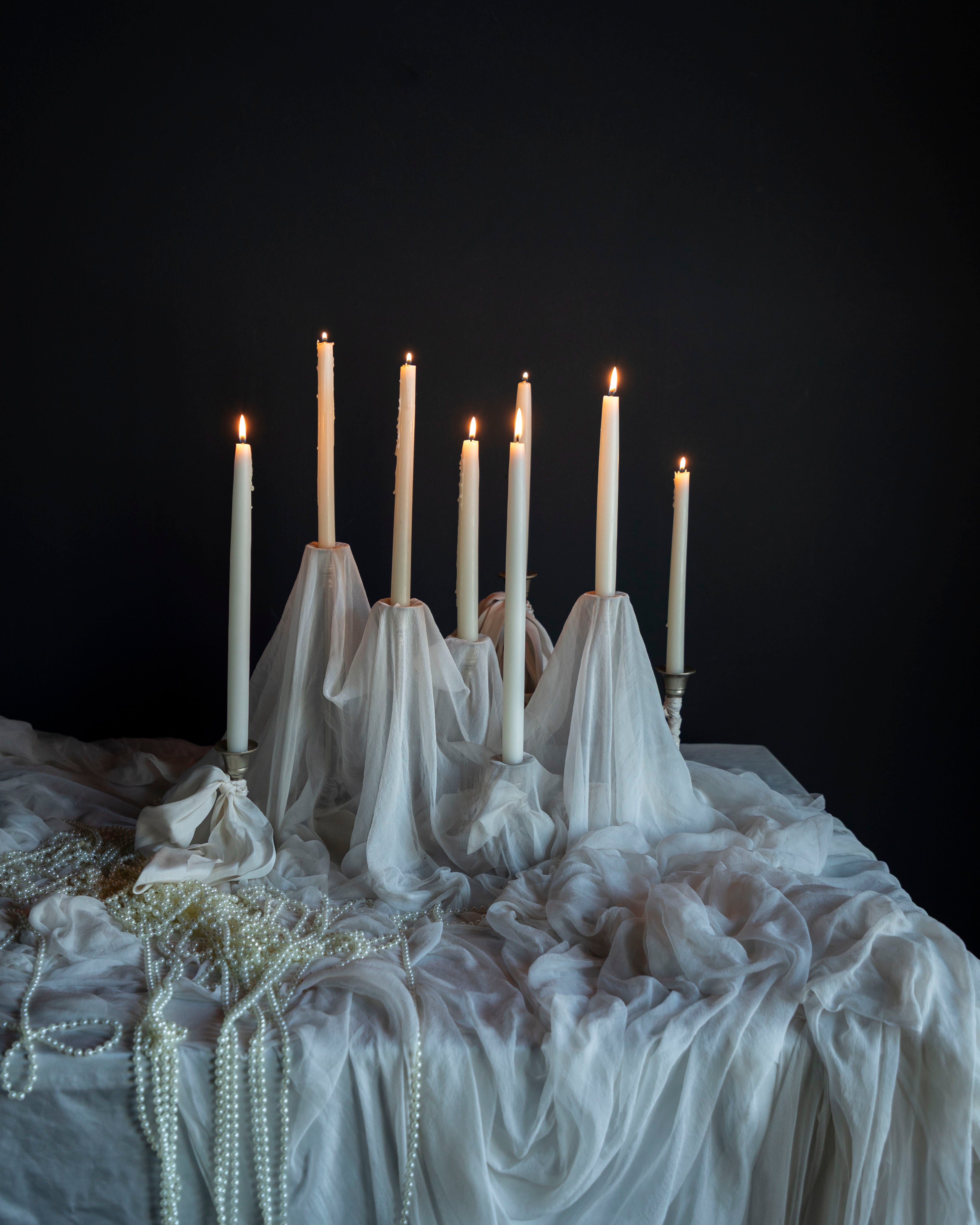 Candelabrum with lit candles on a draped tablecloth against a dark background