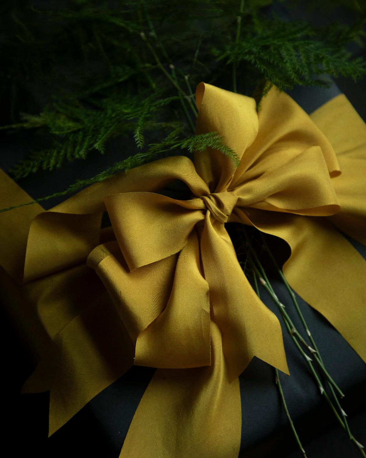 A luxurious gift box wrapped with a silky gold ribbon bow, highlighting its smooth texture and elegant shine, ideal for wedding invitations and appealing to bride-to-be, engaged couples, and florists seeking the finest in luxury gift wrapping