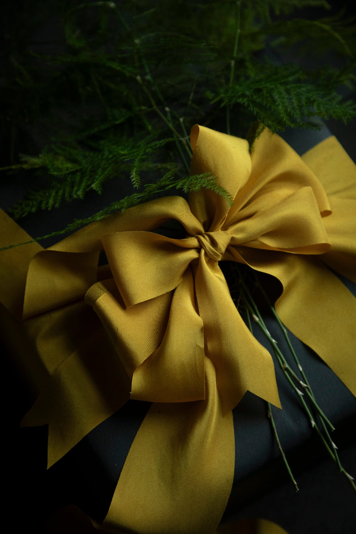 A luxurious gift box wrapped with a silky gold ribbon bow, highlighting its smooth texture and elegant shine, ideal for wedding invitations and appealing to bride-to-be, engaged couples, and florists seeking the finest in luxury gift wrapping