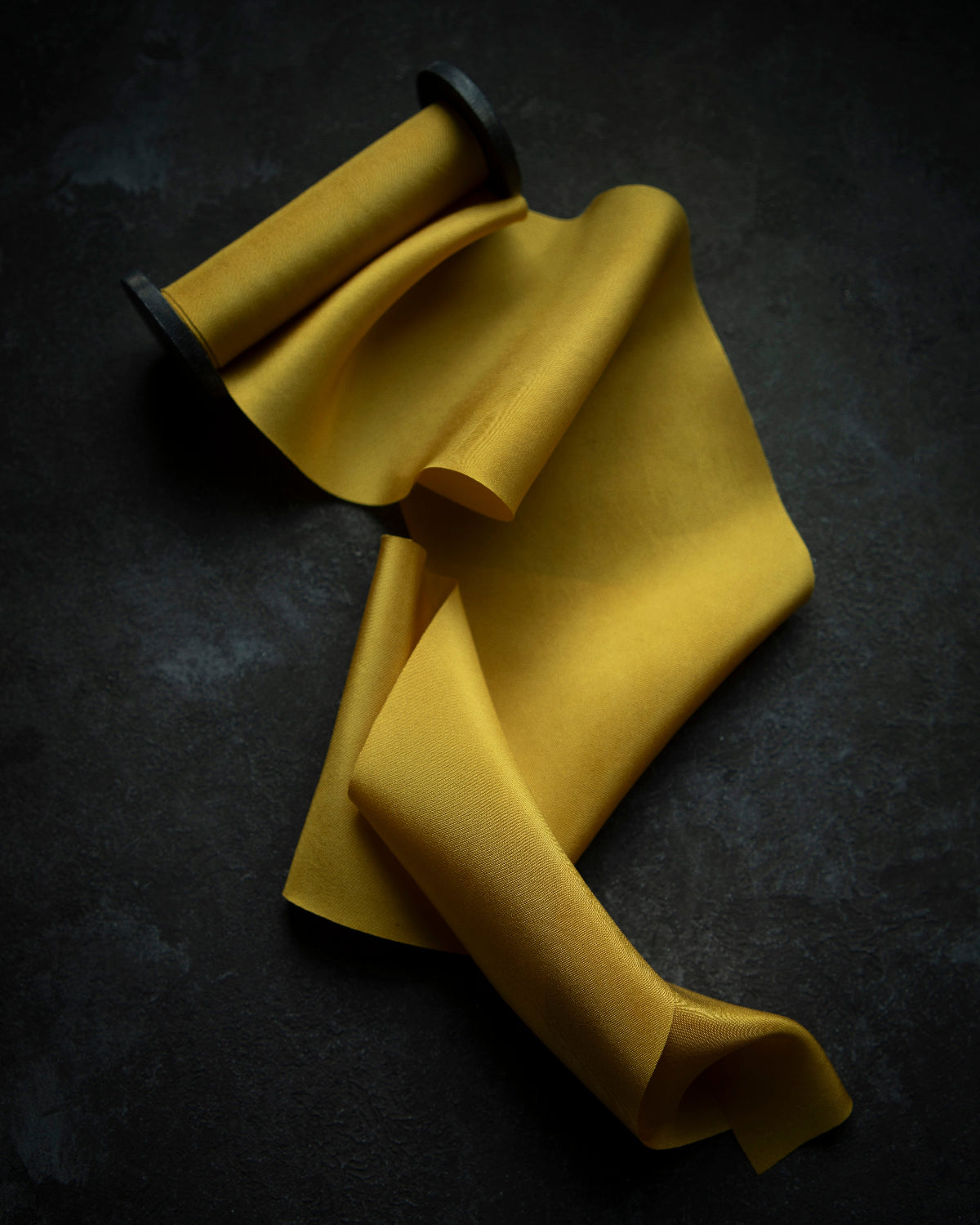 A luxurious plant-dyed silk ribbon in a rich gold hue, elegantly draped, showcasing its soft texture and delicate sheen. Ideal for wrapping bridal bouquets, this ribbon is perfect for brides-to-be, engaged couples, and florists looking to add a touch of sophistication to wedding arrangements.