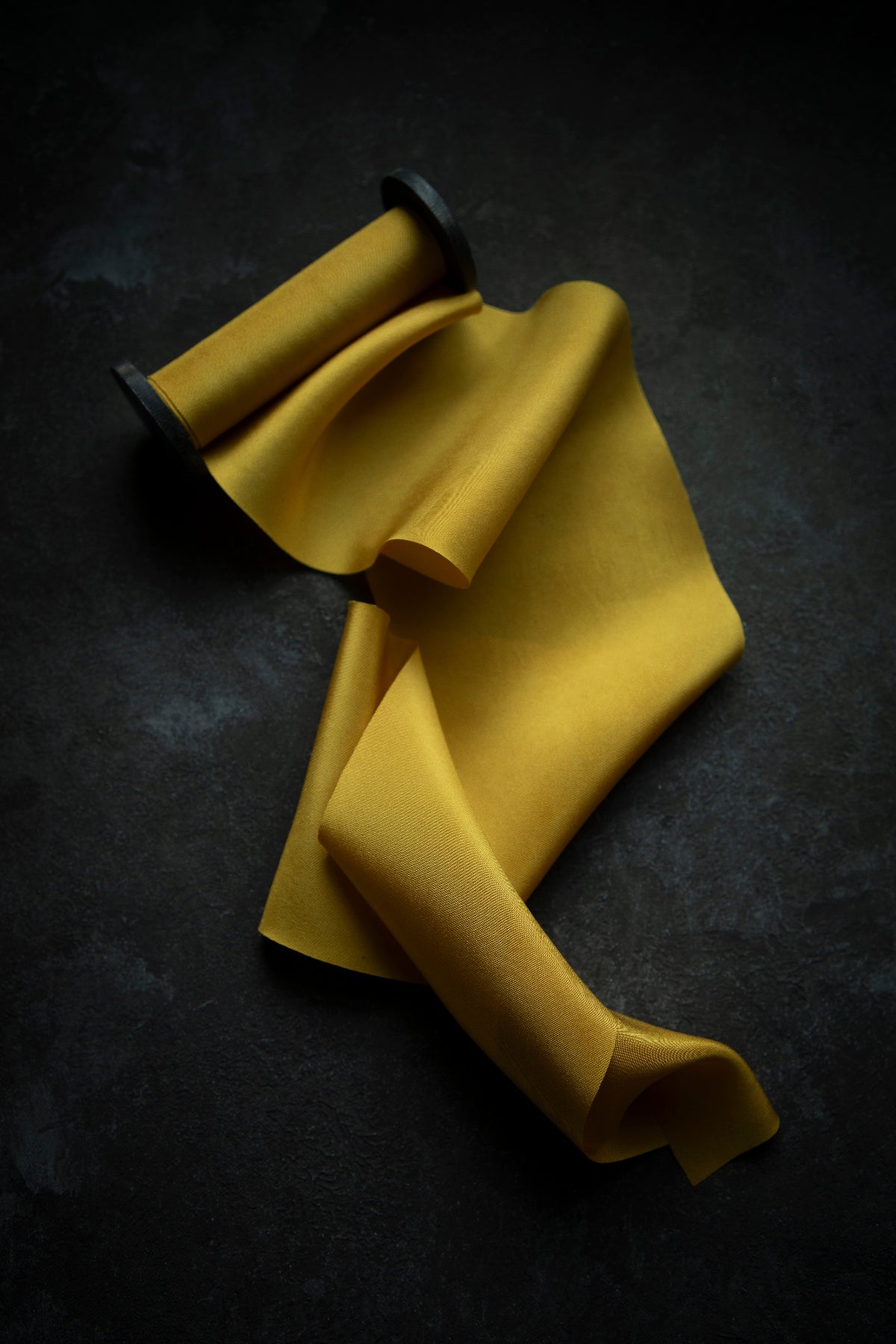A luxurious plant-dyed silk ribbon in a rich gold hue, elegantly draped, showcasing its soft texture and delicate sheen. Ideal for wrapping bridal bouquets, this ribbon is perfect for brides-to-be, engaged couples, and florists looking to add a touch of sophistication to wedding arrangements.
