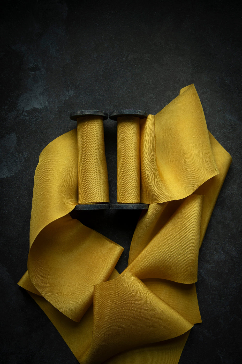 A luxurious plant-dyed silk ribbon in a rich gold hue, elegantly draped, showcasing its soft texture and delicate sheen. Ideal for wrapping bridal bouquets, this ribbon is perfect for brides-to-be, engaged couples, and florists looking to add a touch of sophistication to wedding arrangements.