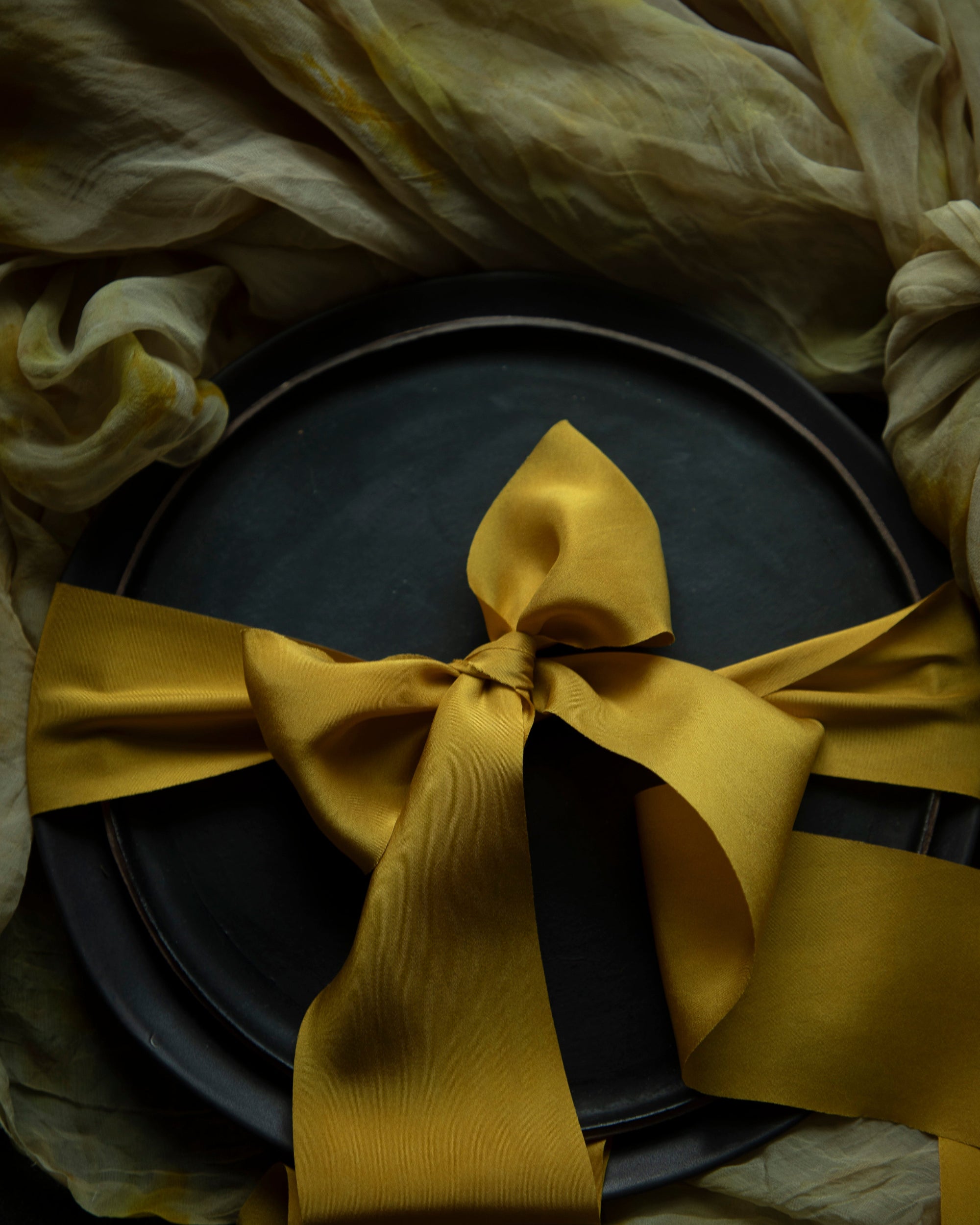 A luxurious plant-dyed silk ribbon in a rich gold hue, elegantly draped, showcasing its soft texture and delicate sheen. Ideal for wrapping bridal bouquets, this ribbon is perfect for brides-to-be, engaged couples, and florists looking to add a touch of sophistication to wedding arrangements.