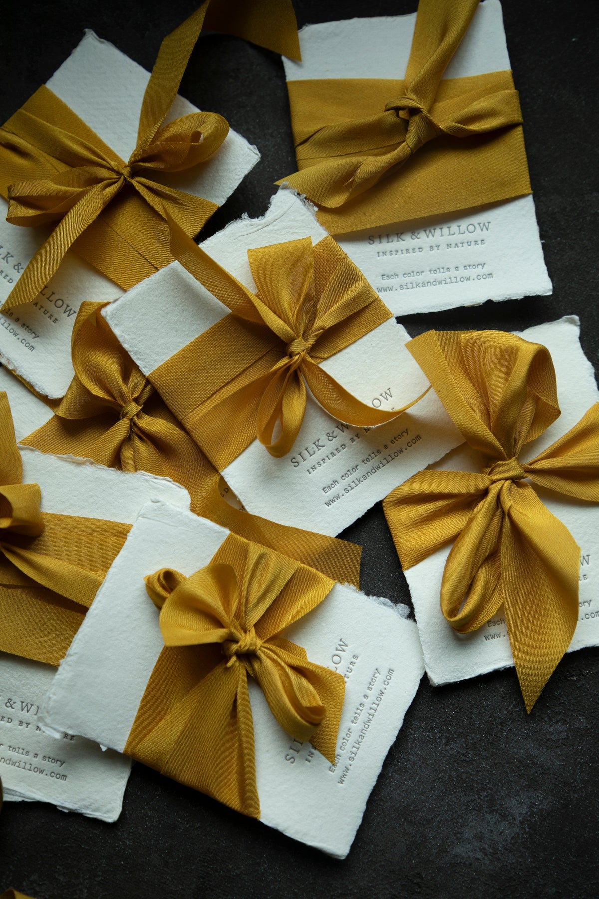 A luxurious plant-dyed silk ribbon in a rich gold hue, tied around a silk and willow letterpress note card showcasing its soft texture and delicate sheen. Ideal for wrapping bridal bouquets, this ribbon is perfect for brides-to-be, engaged couples, and florists looking to add a touch of sophistication to wedding arrangements.