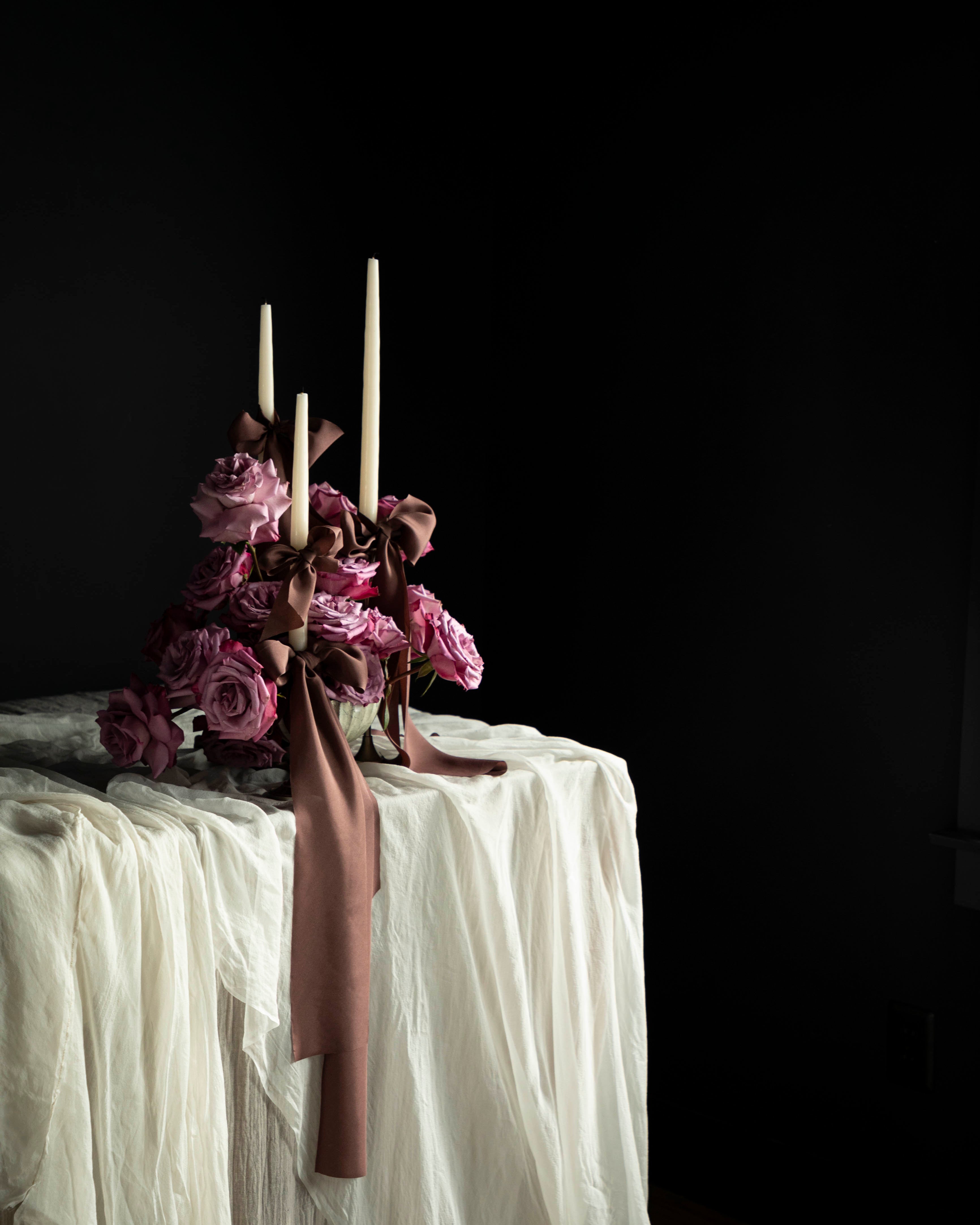 wedding tablescape with draping textiles and rose floral arrangement adorned with silk ribbons.