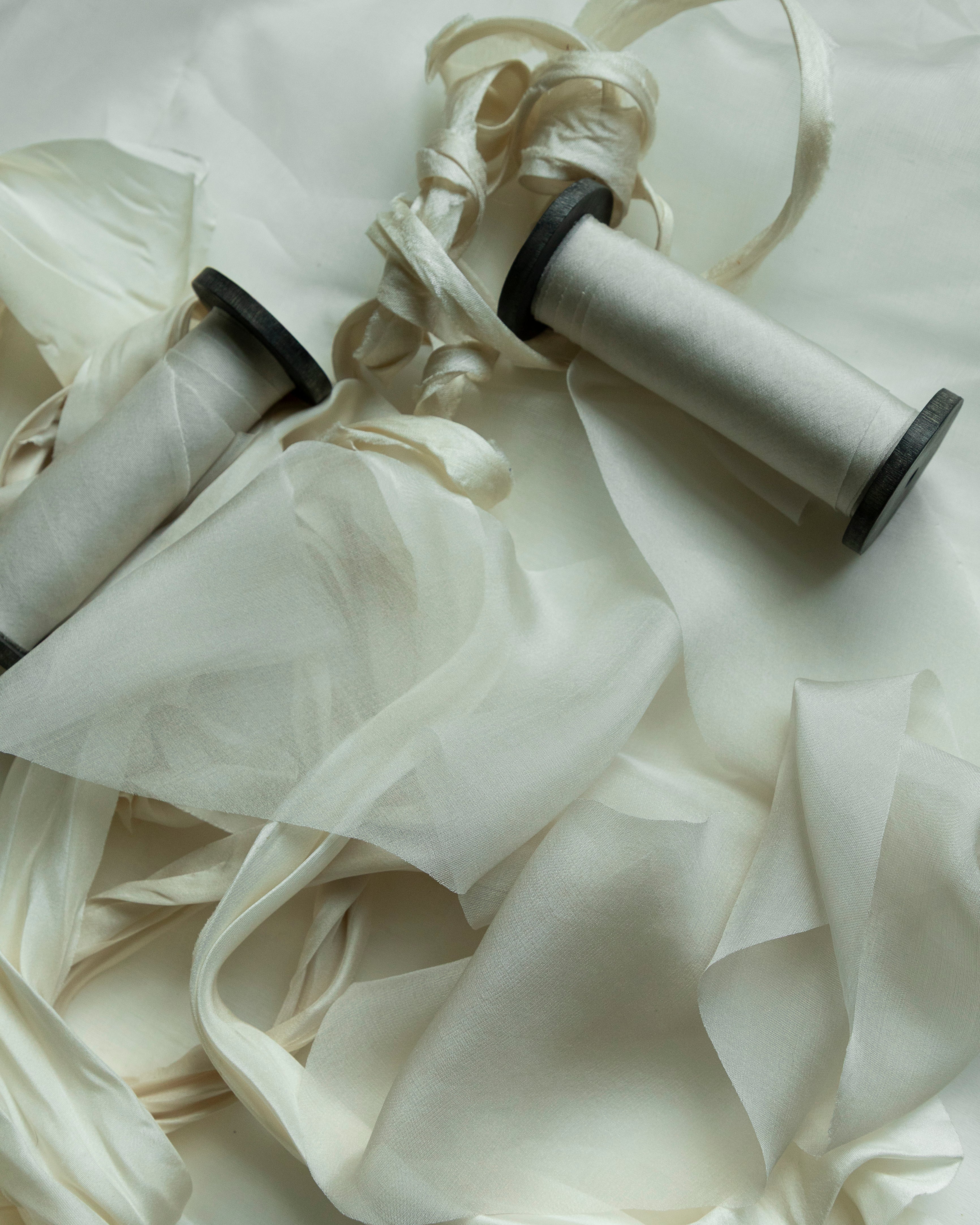 Two spools of dove silk ribbon on black vintage spool on a white background