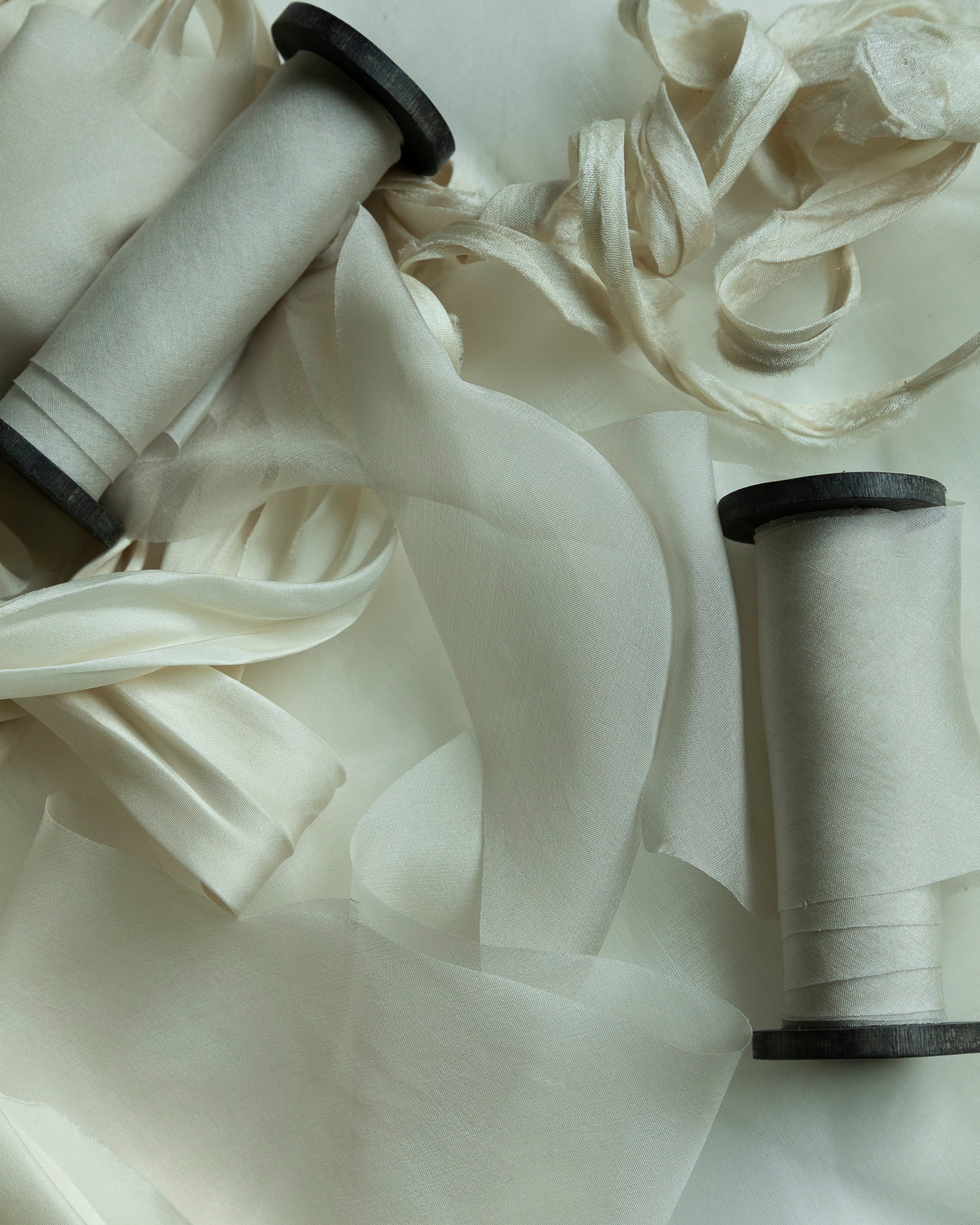 Two spools of white ribbon on a light background