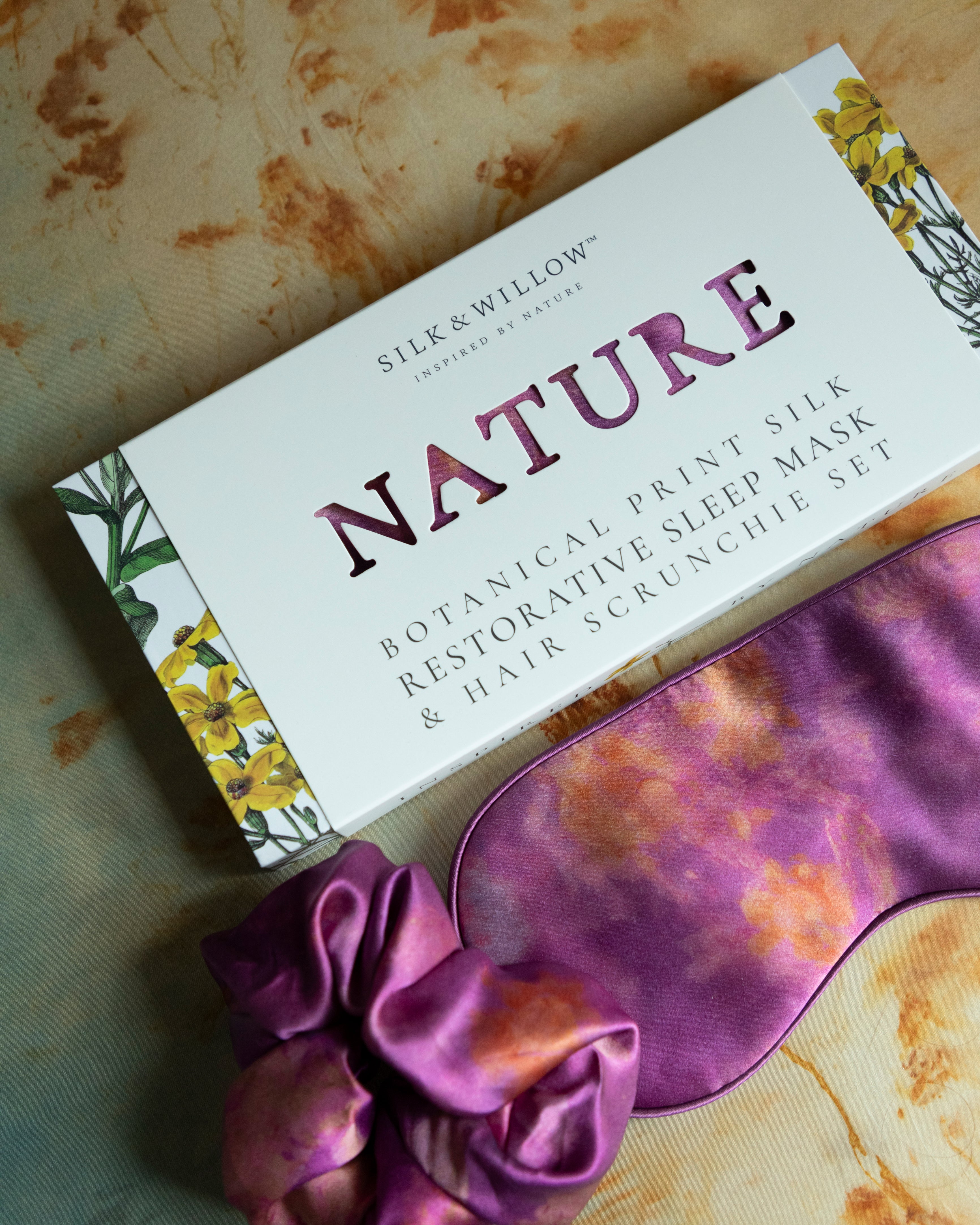A luxurious silk sleep mask and hair scrunchie set featuring delicate botanical patterns, elegantly displayed in a sustainable gift box, perfect for a sophisticated and eco-conscious touch.