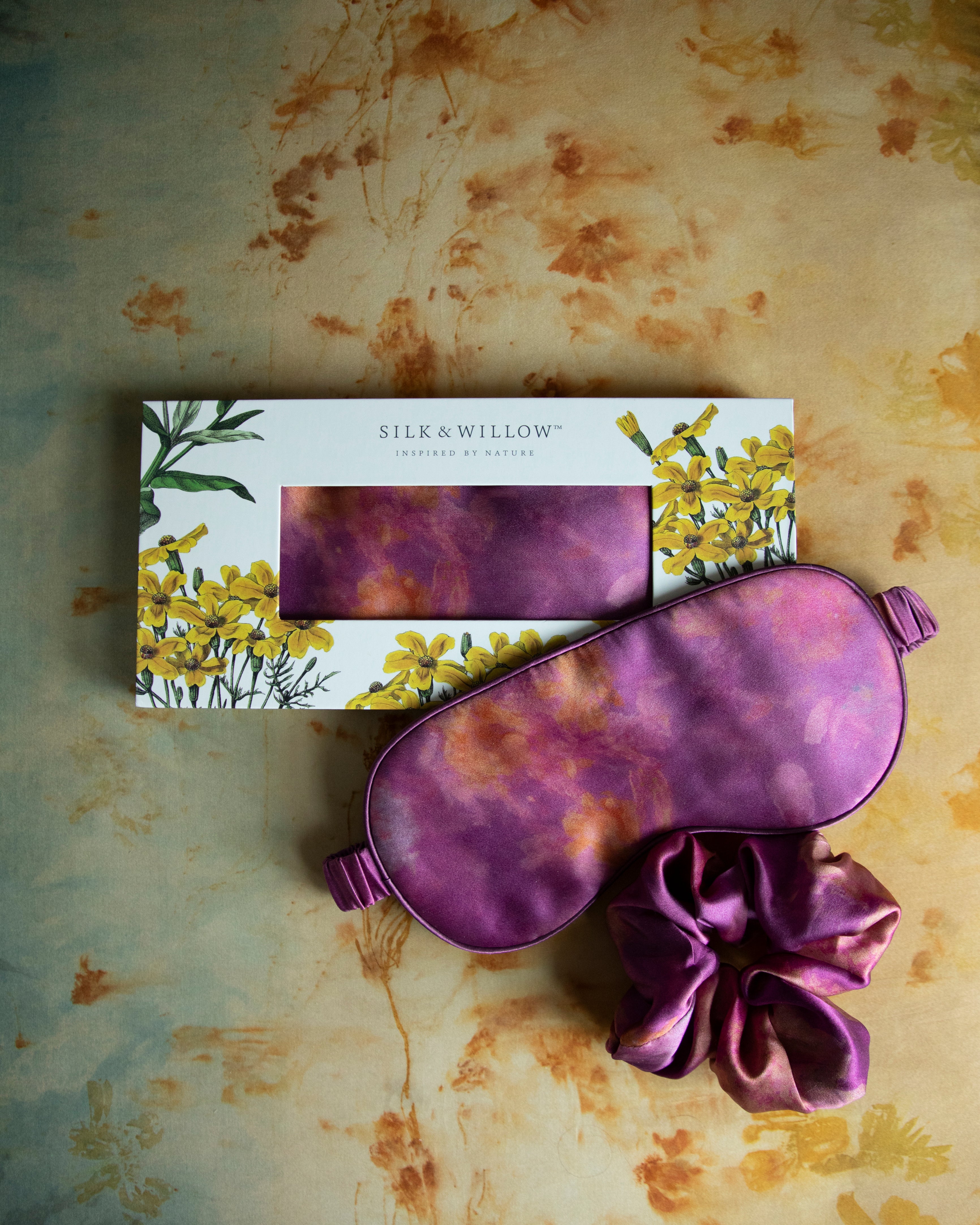 A luxurious silk sleep mask and hair scrunchie set featuring delicate botanical patterns, elegantly displayed in a sustainable gift box, perfect for a sophisticated and eco-conscious touch.