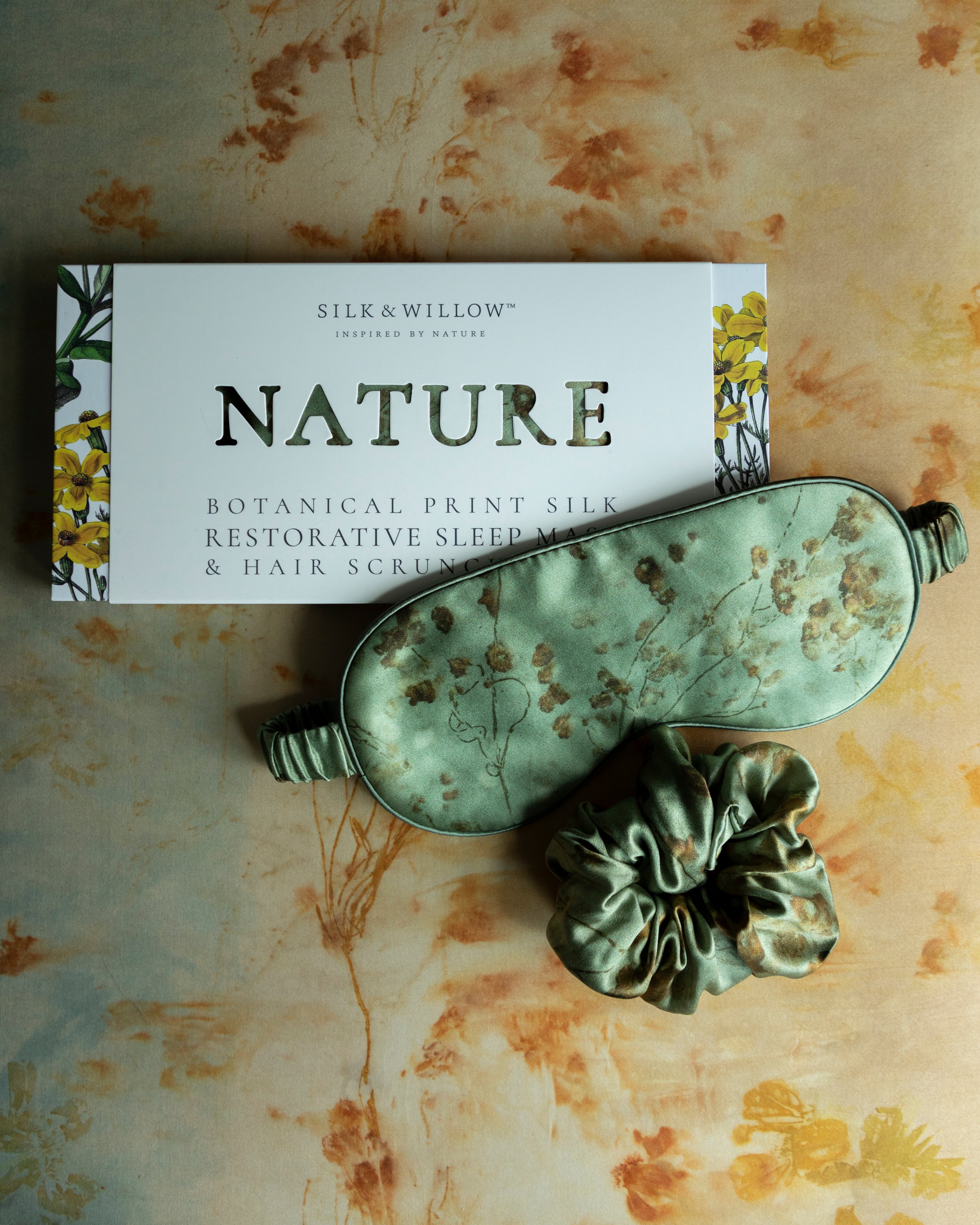 luxury silk sleep eye mask placed next to gift packaging with "nature" dye cut.
