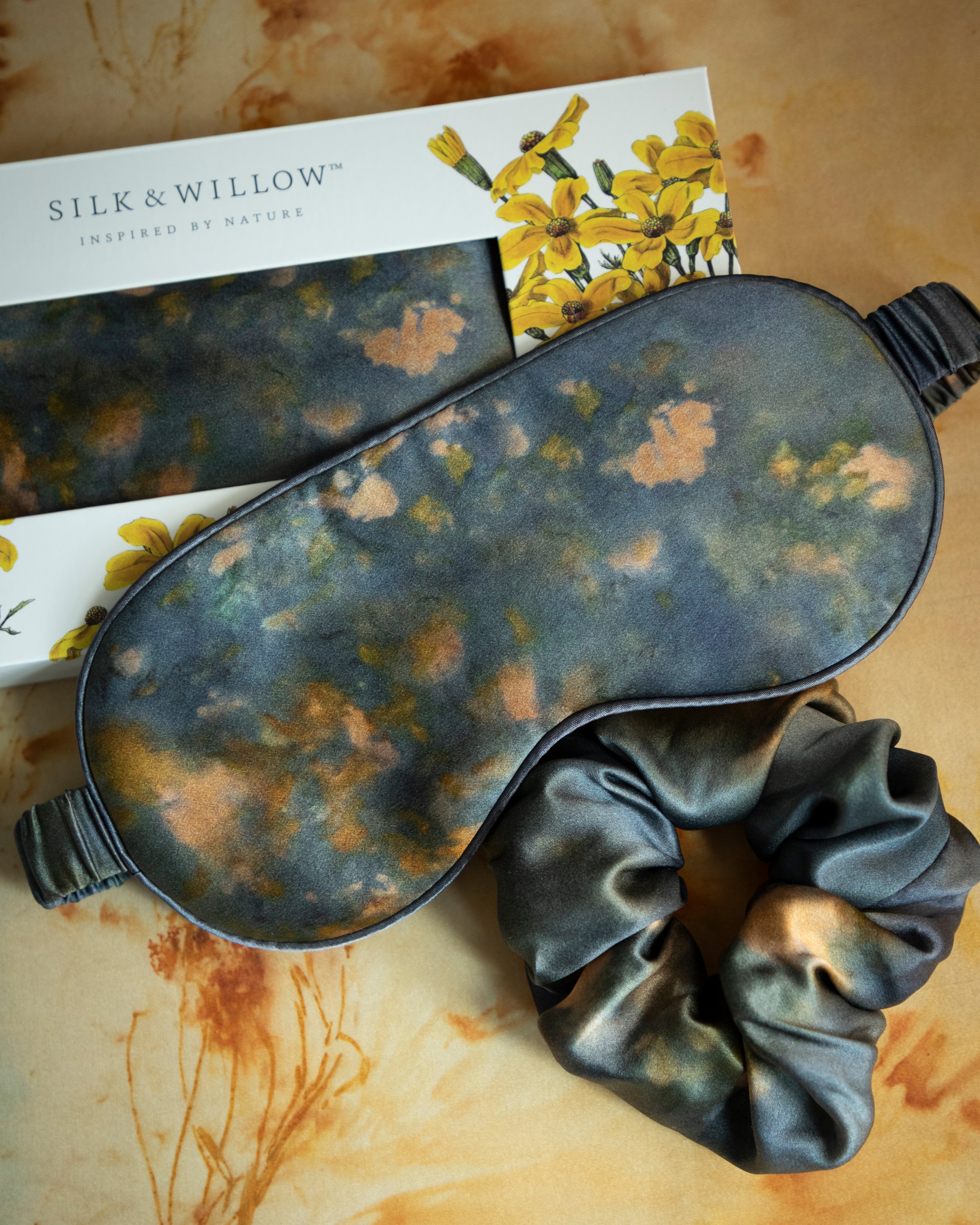 A luxurious silk sleep mask and hair scrunchie set featuring delicate botanical patterns, elegantly displayed in a sustainable gift box, perfect for a sophisticated and eco-conscious touch.