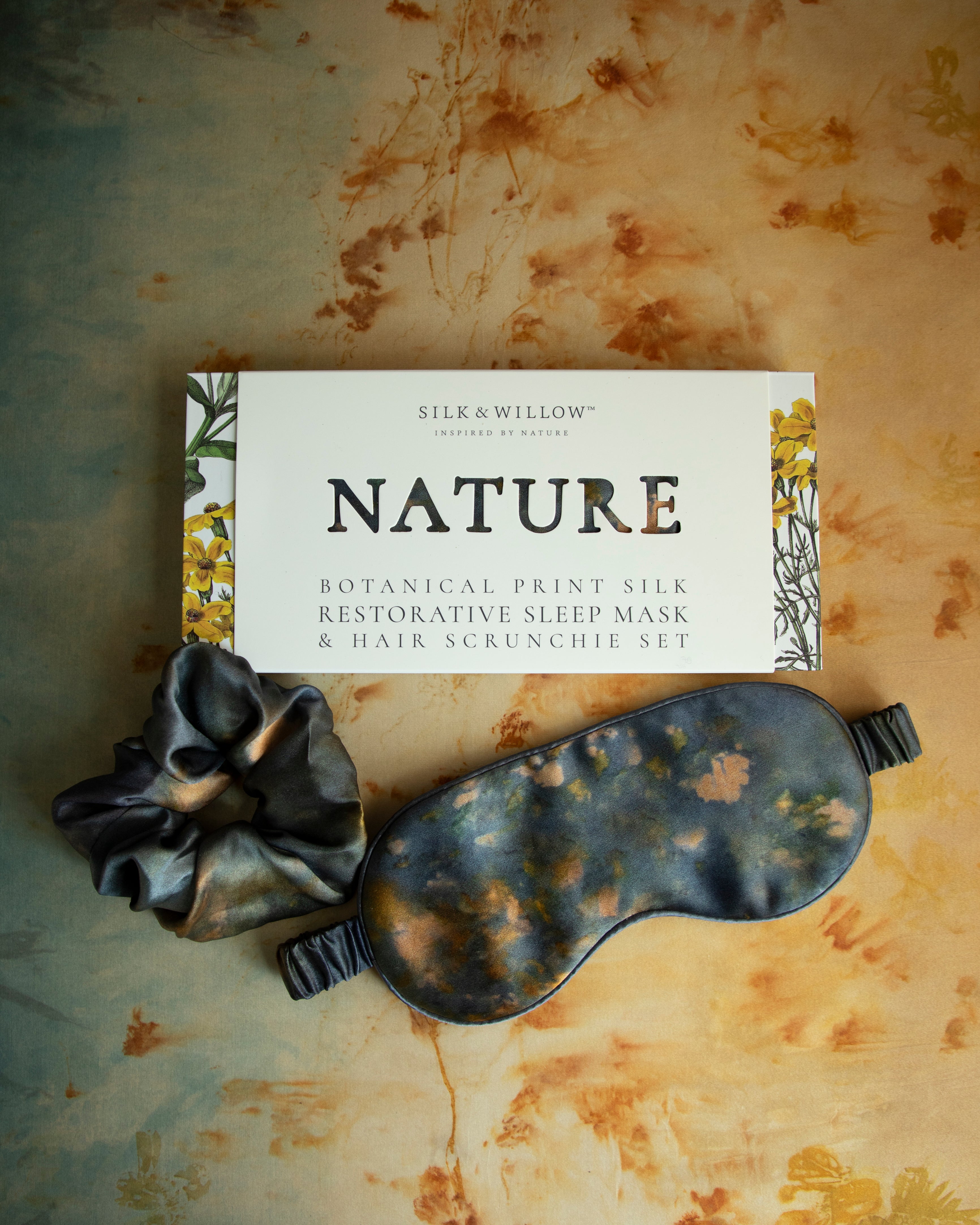 A luxurious silk sleep mask and hair scrunchie set featuring delicate botanical patterns, elegantly displayed in a sustainable gift box, perfect for a sophisticated and eco-conscious touch.