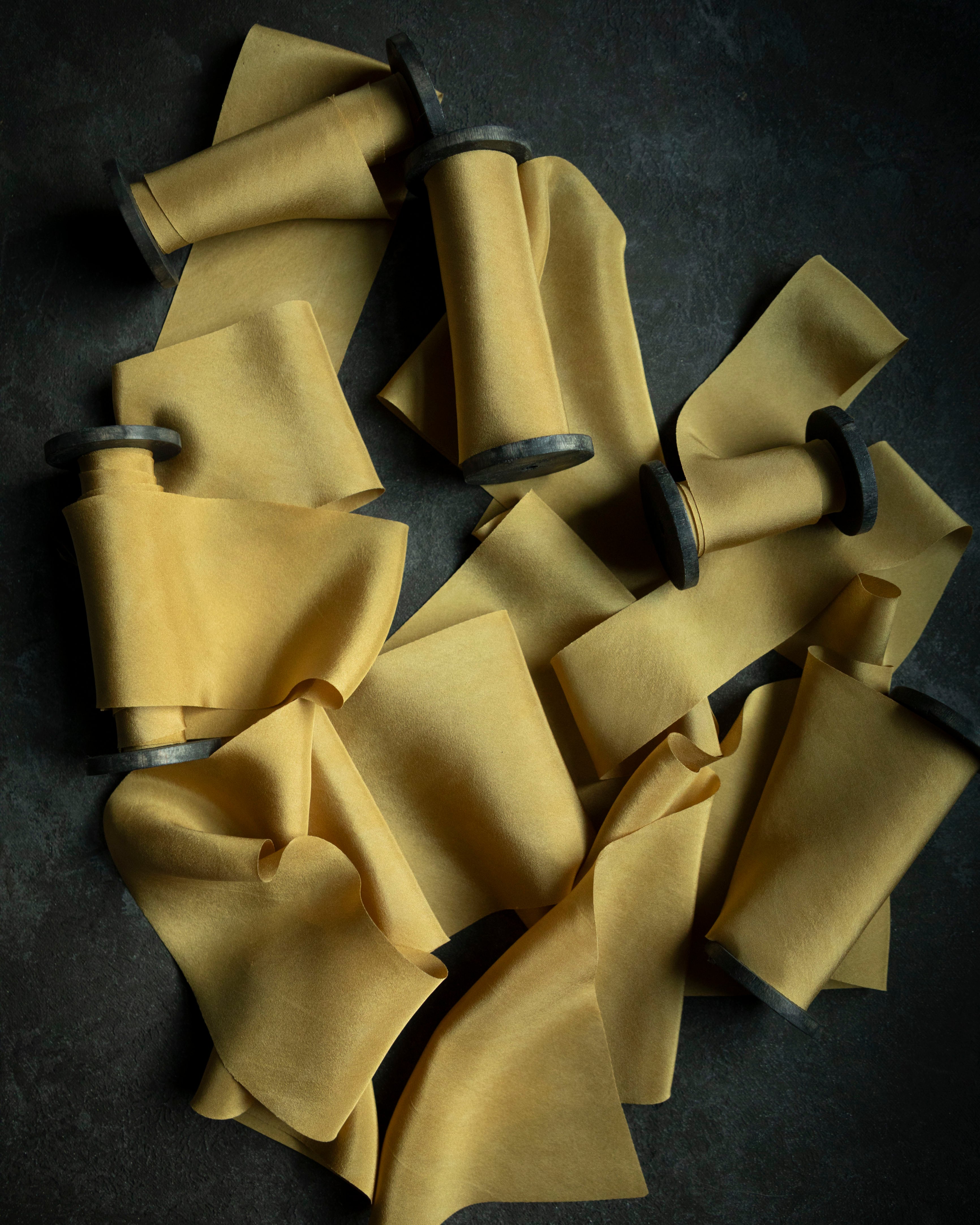 gold silk ribbon for wedding flowers. premium florist ribbon on wooden spools with black background