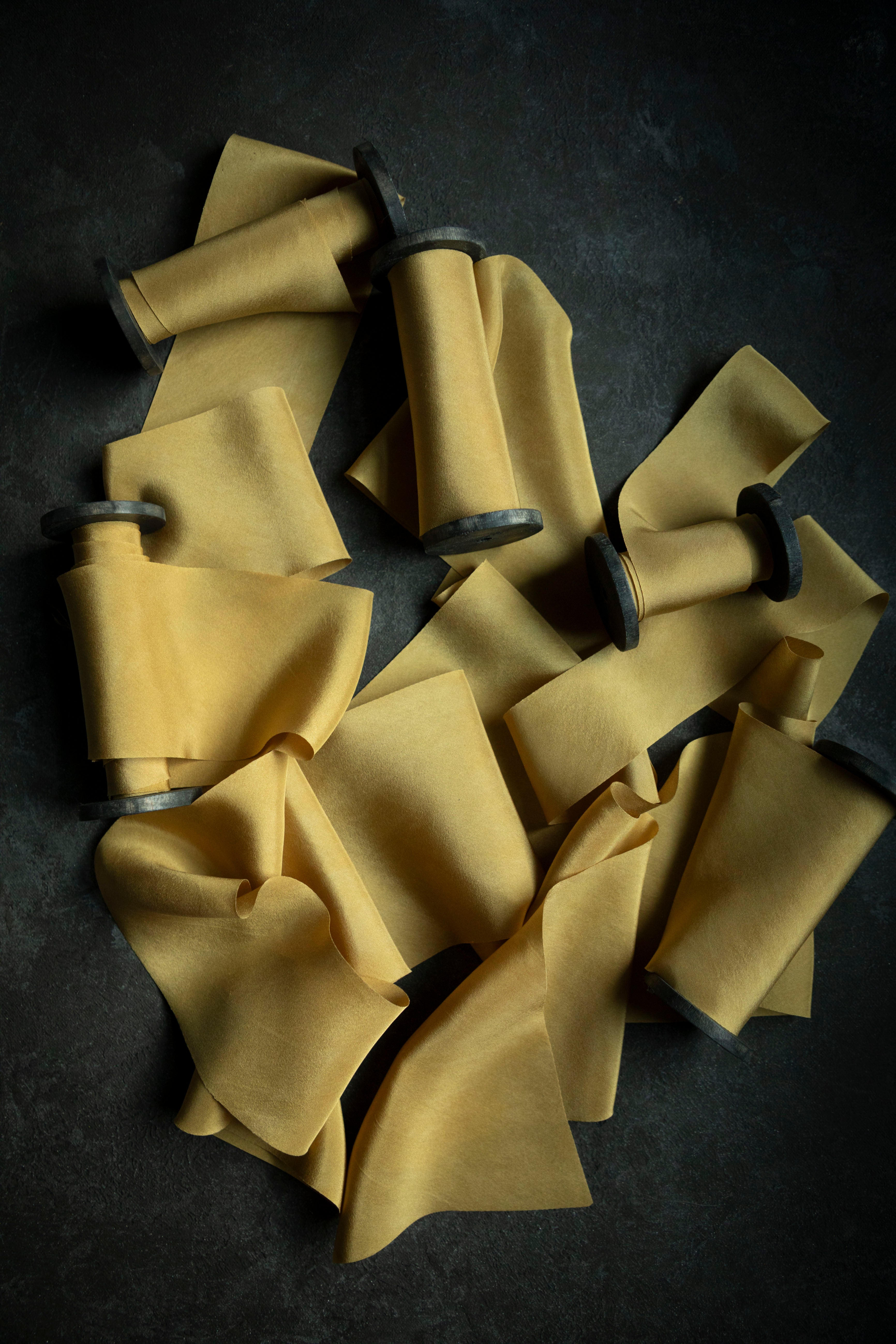 gold silk ribbon for wedding flowers. premium florist ribbon on wooden spools with black background