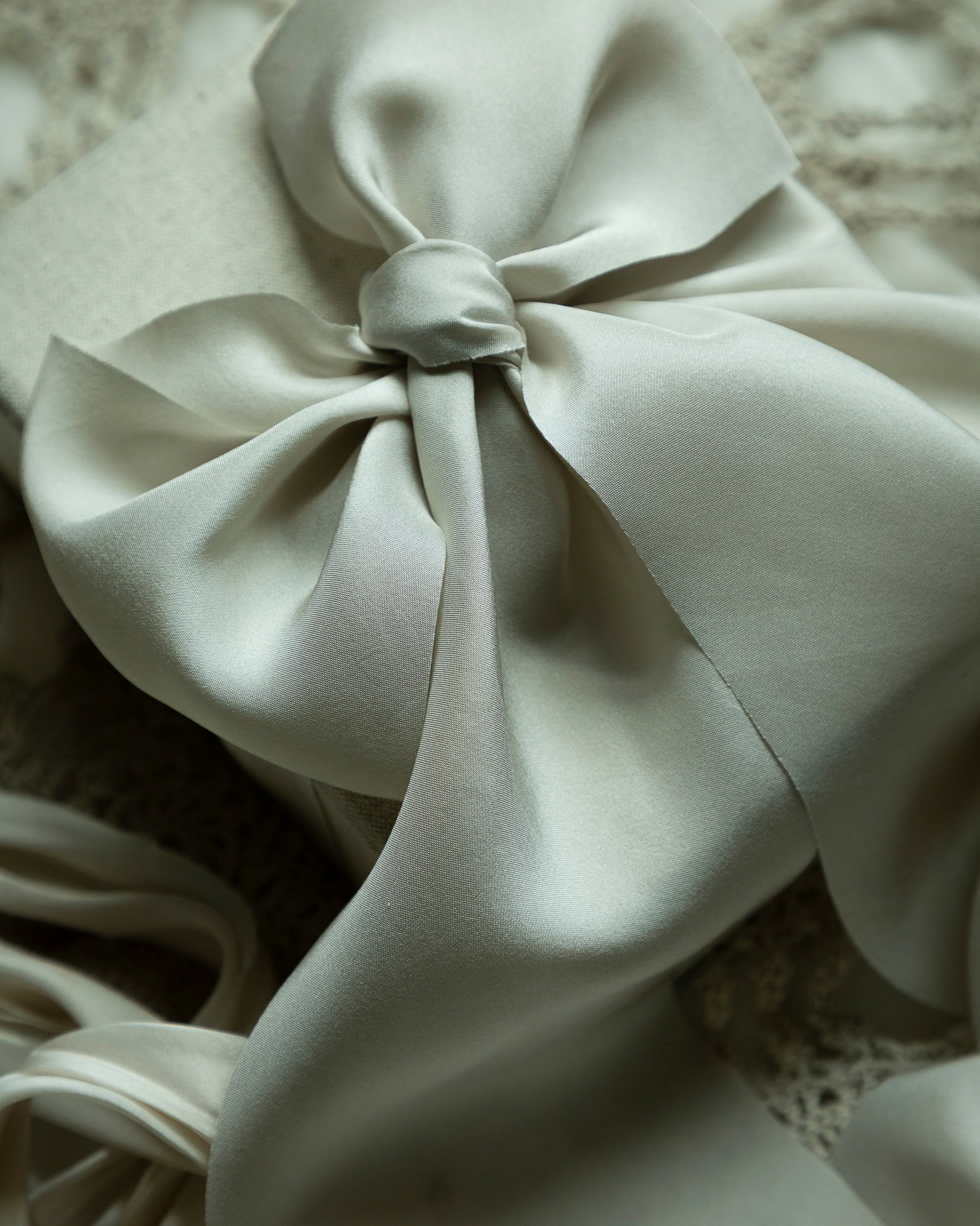 Close-up of a light gray fabric bow on a textured surface