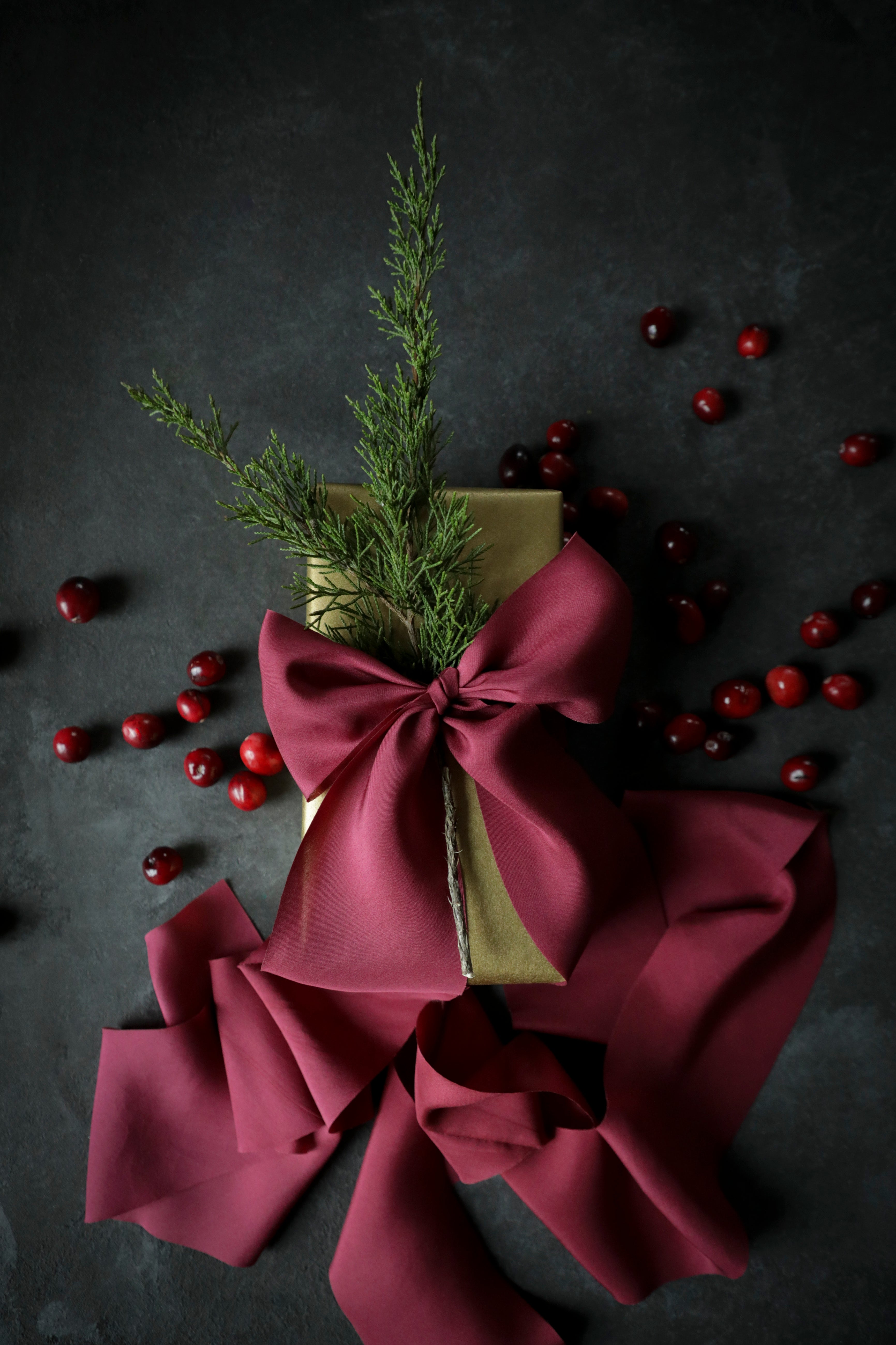 holiday red gift wrapping ribbon on a present. kraft paper box with ever greens gift topper.