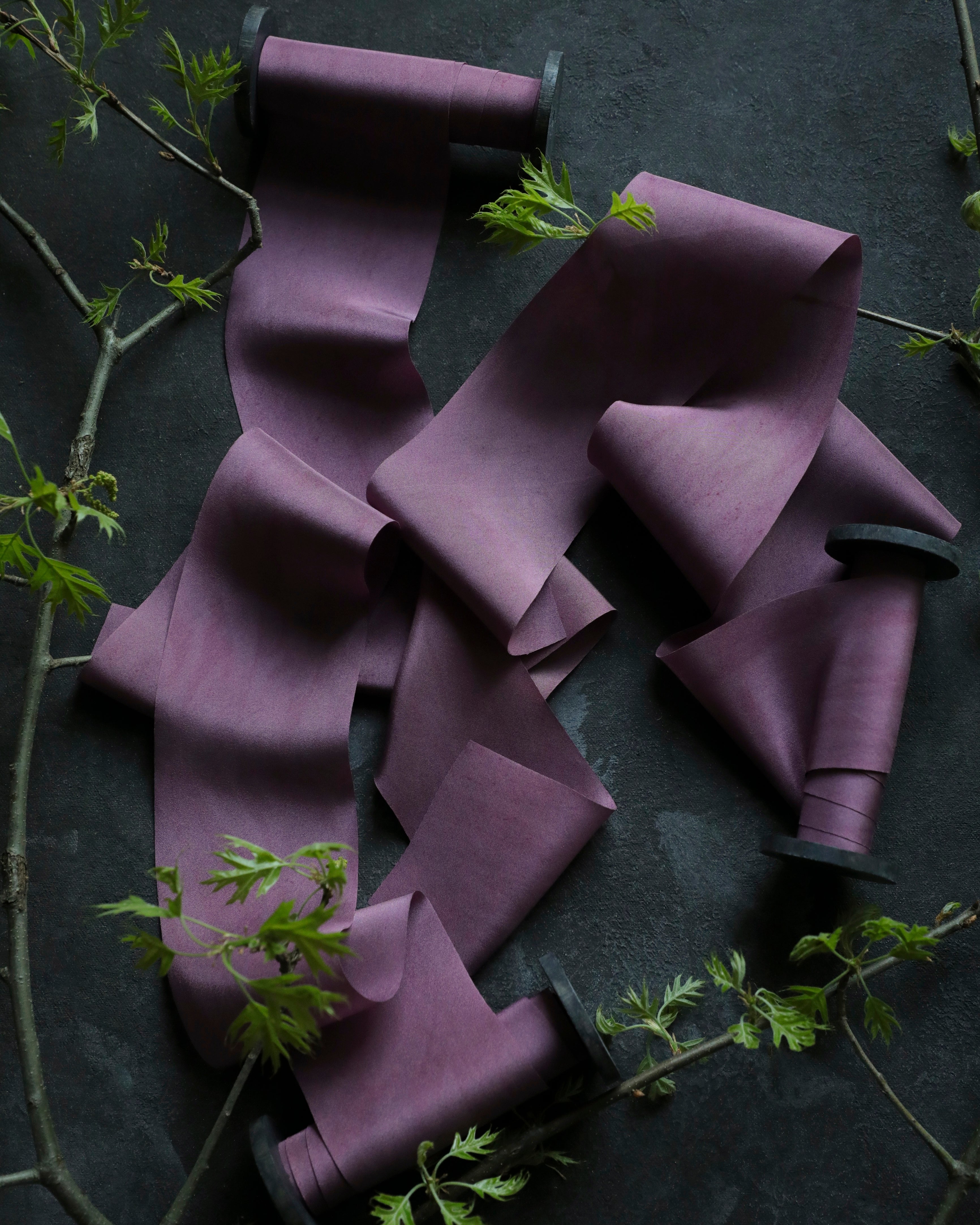 purple ribbon on wood spool opened on a black textured background