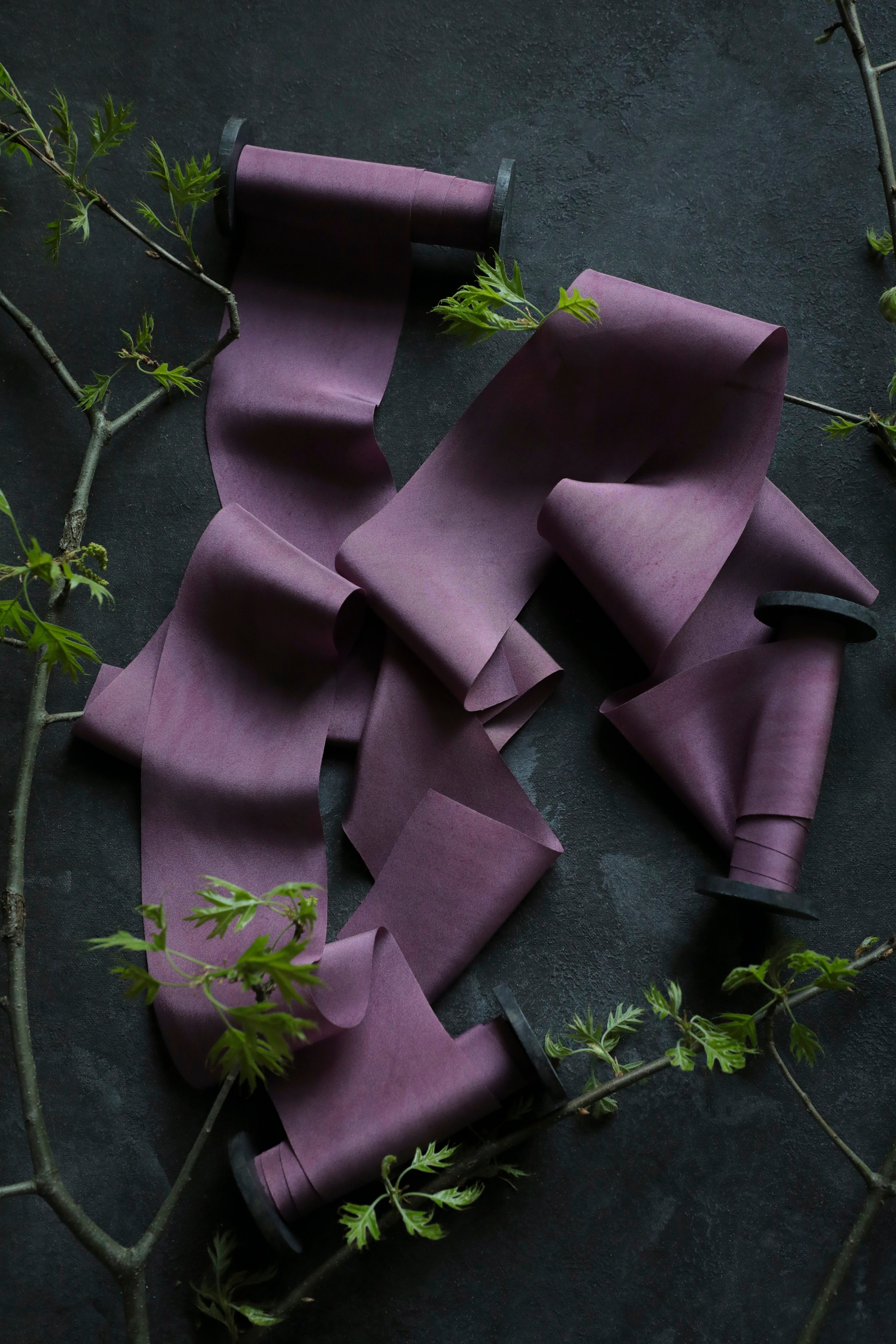 purple ribbon on wood spool opened on a black textured background