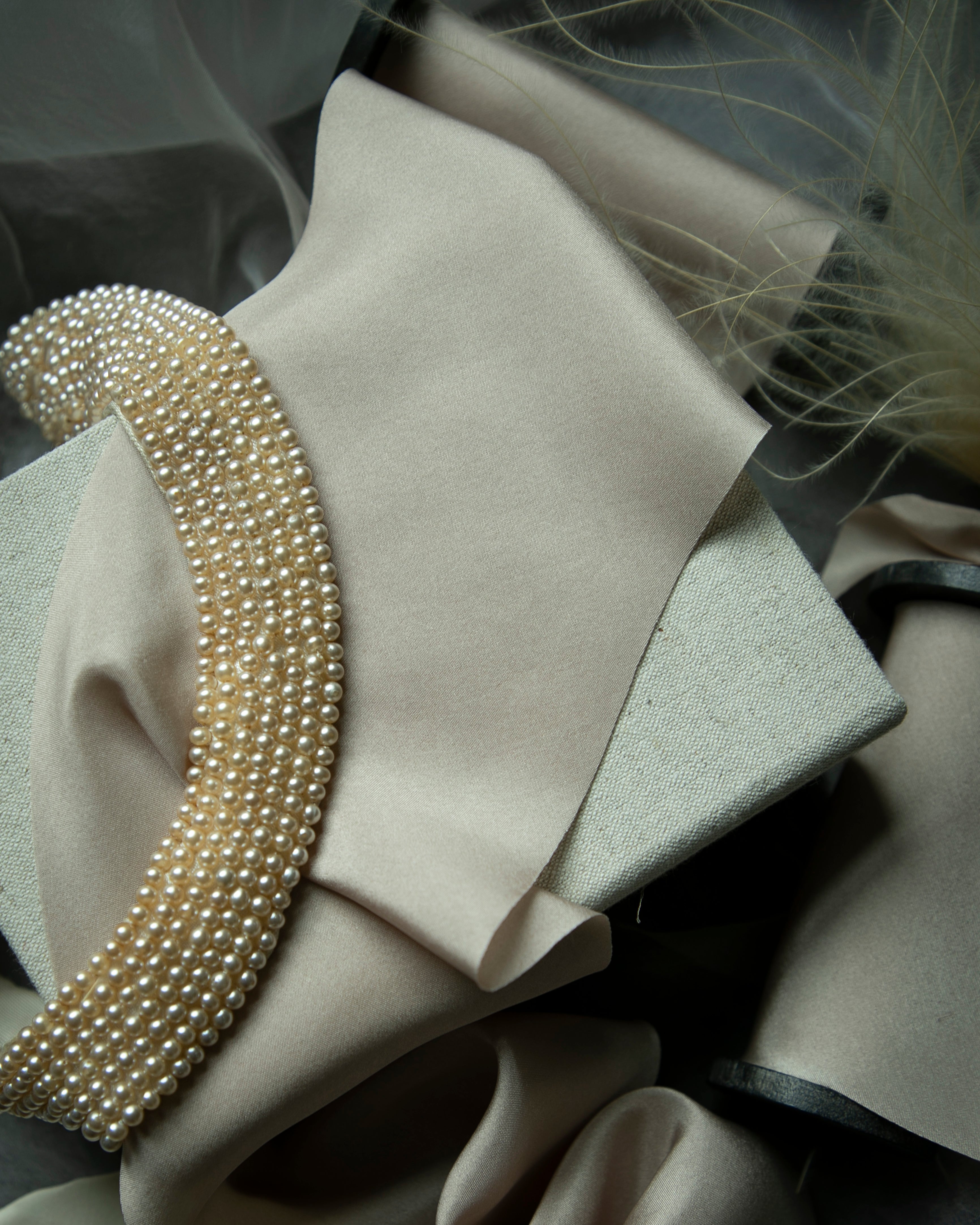 Close-up of pearl-colored silk ribbon with a pearl-like trim on a dark background