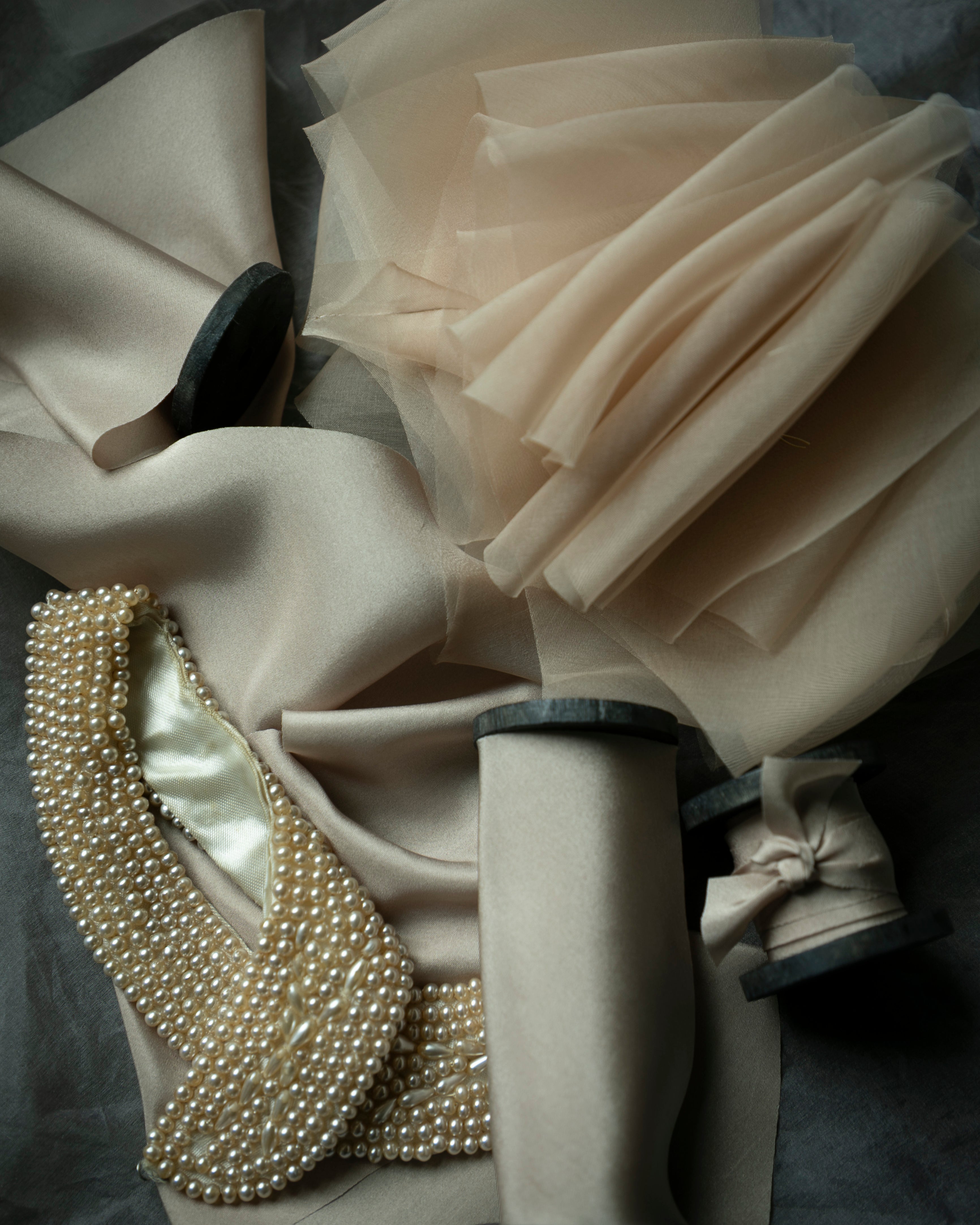 Close-up of a decorative item with fabric and pearl details on a dark background