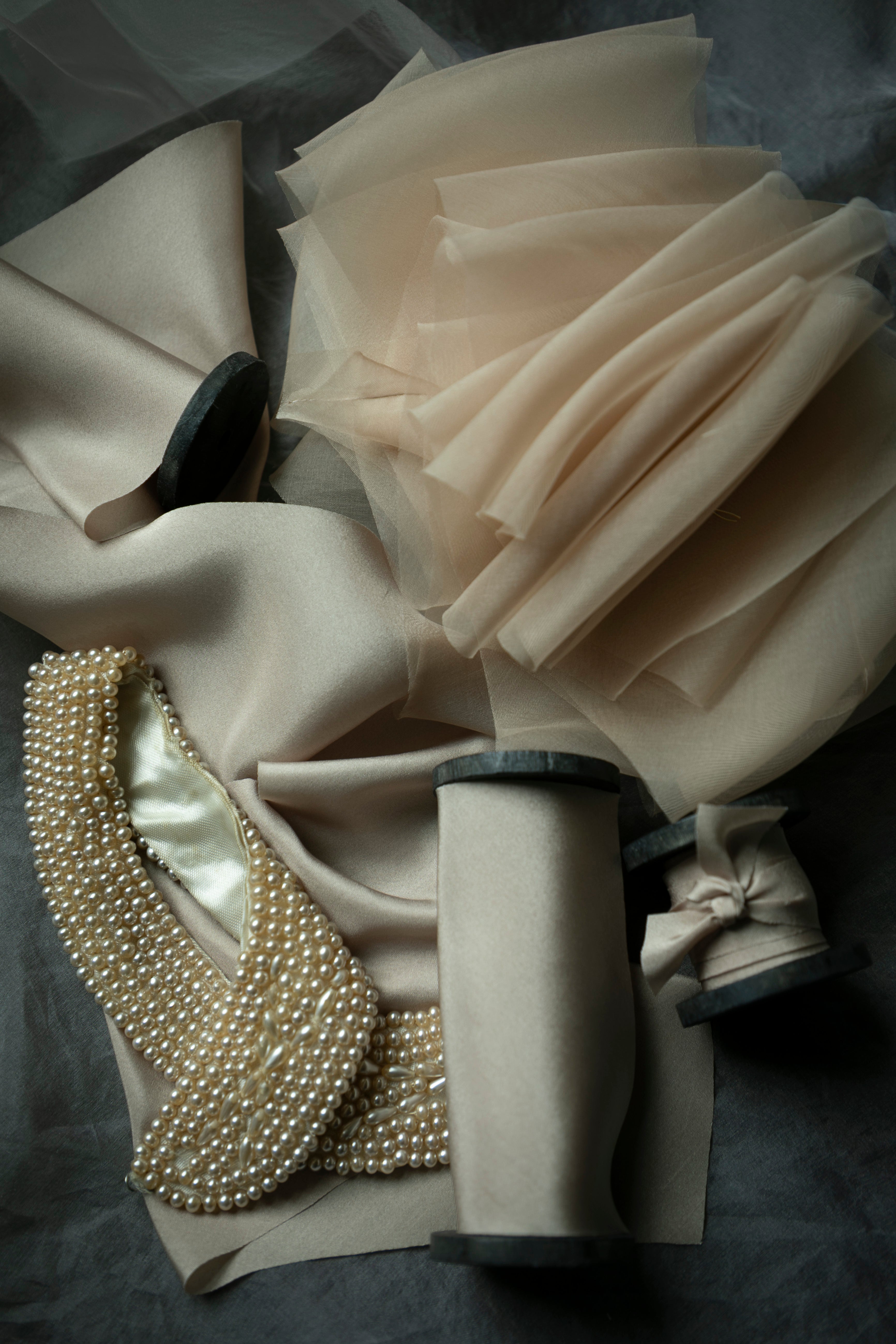 Close-up of a decorative item with fabric and pearl details on a dark background