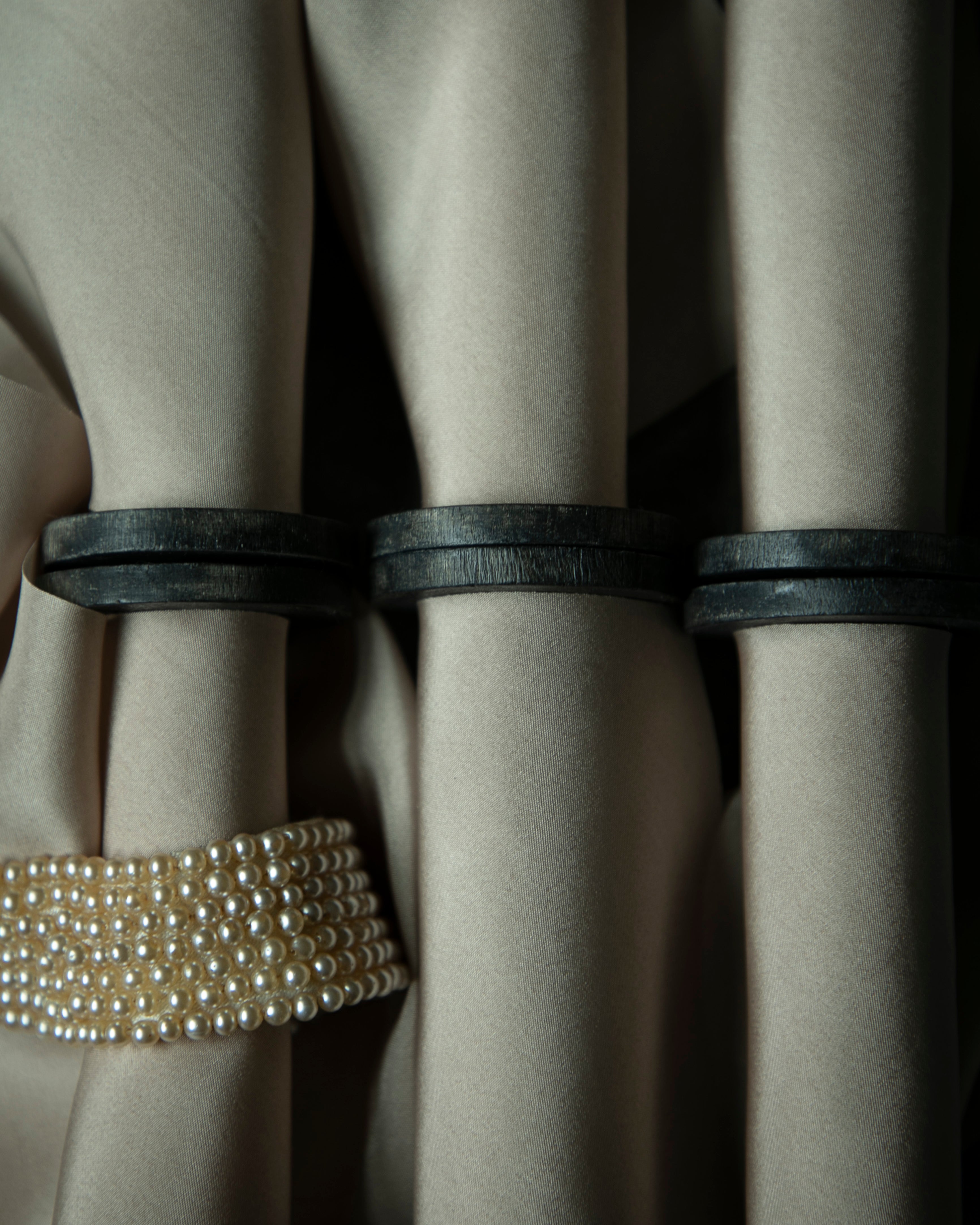 Close-up of beige ribbon on vintage wood spools paired with a vintage pearl necklace.