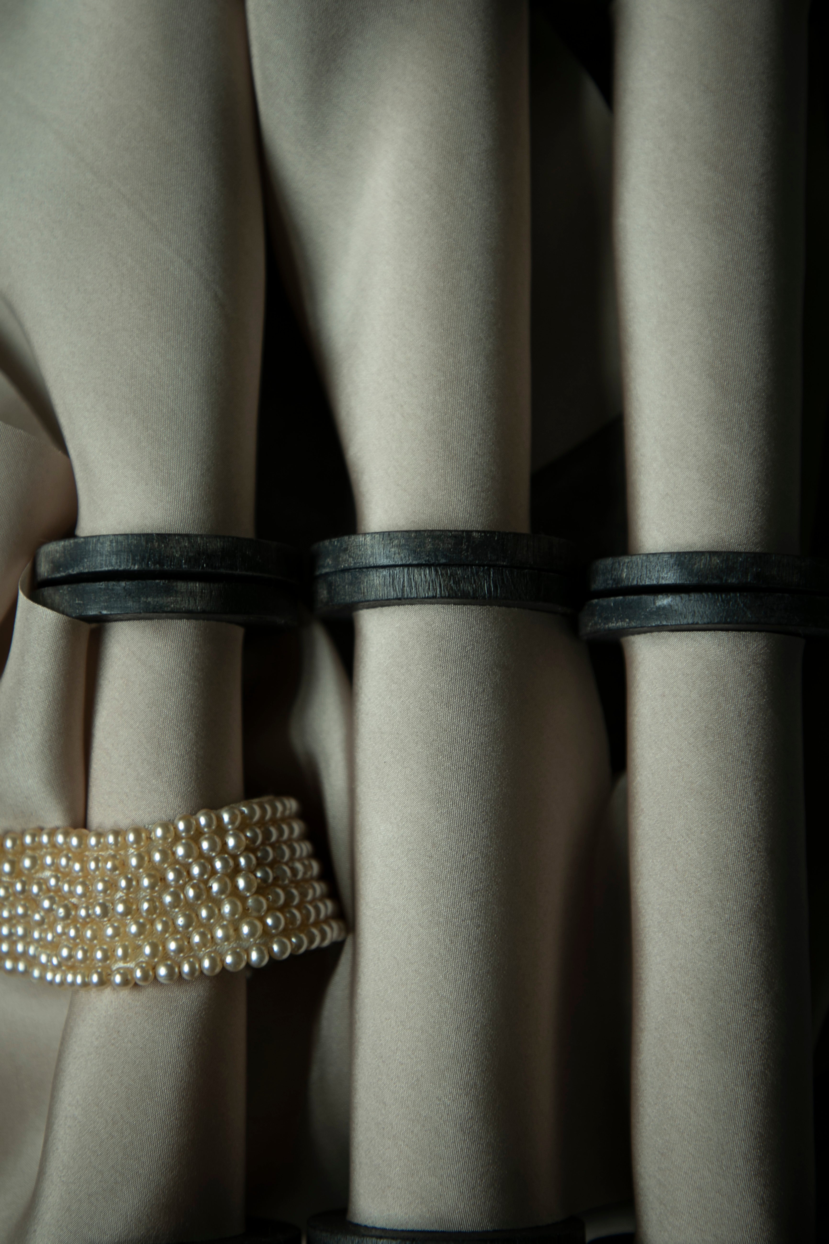 Close-up of beige ribbon on vintage wood spools paired with a vintage pearl necklace.