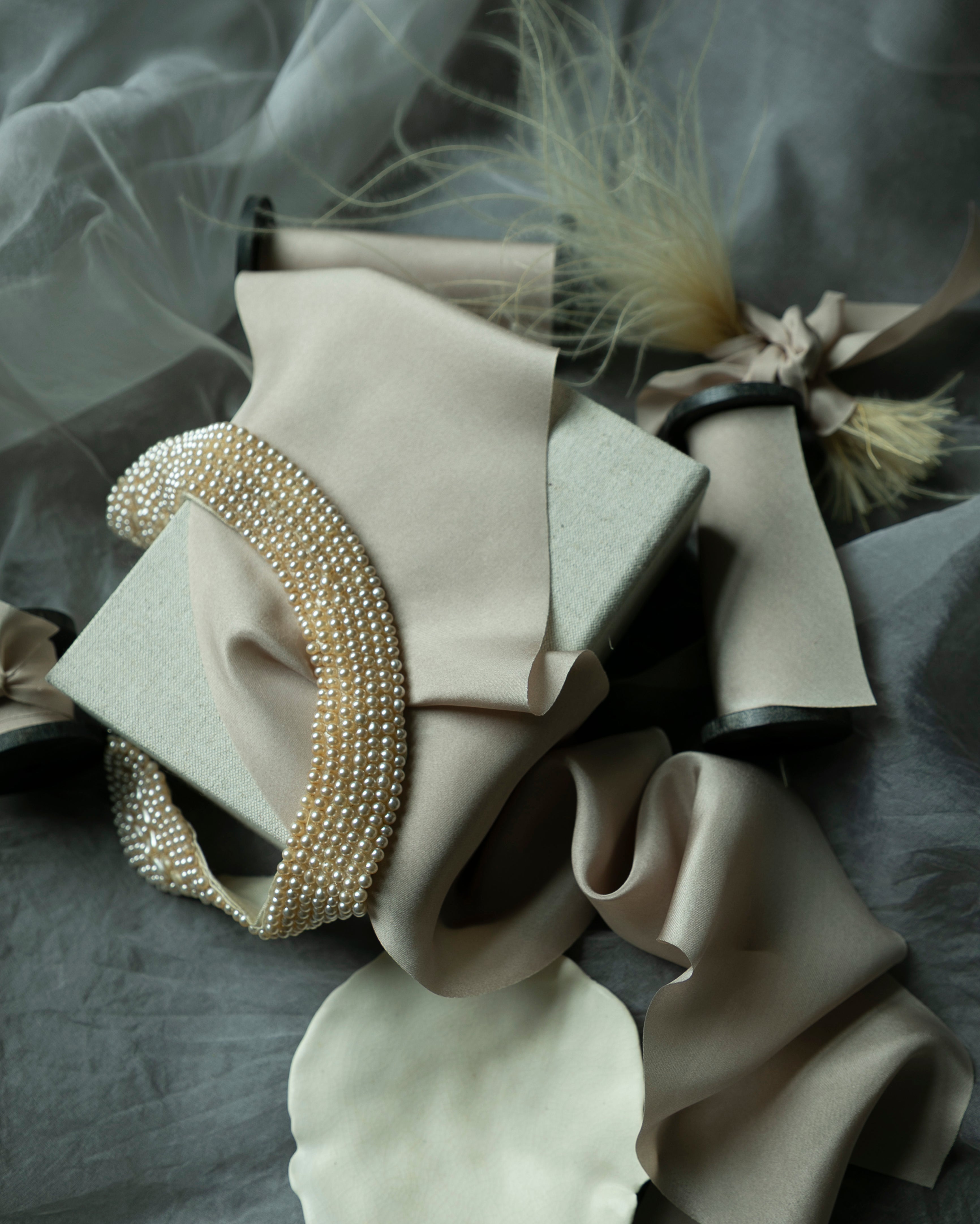 Decorative headband with pearls and feathers on a gray fabric background