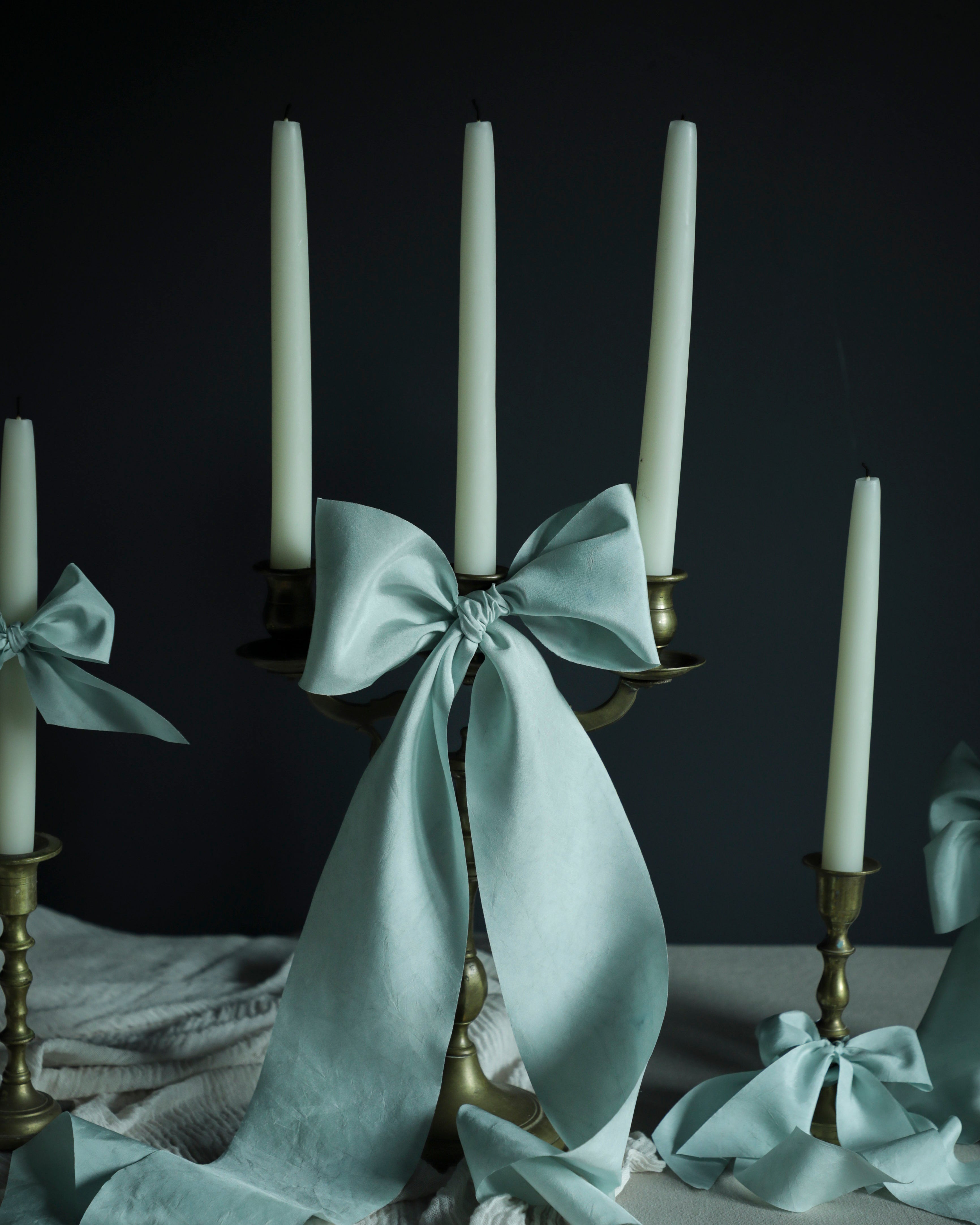 Candle holder with a baby blue bow and candles on a dark background
