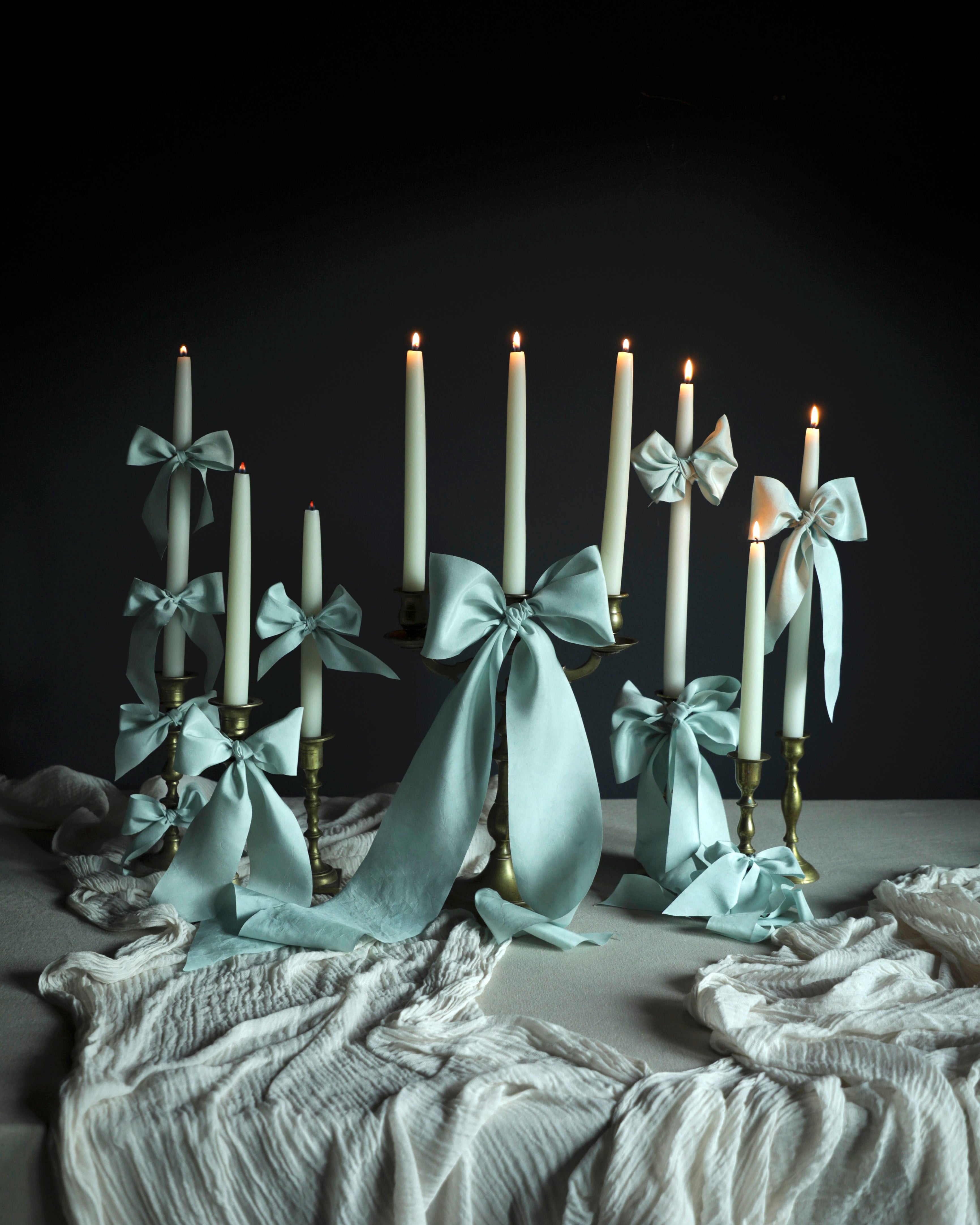 Table centerpiece decor with Candlesticks with light blue ribbons on a dark background