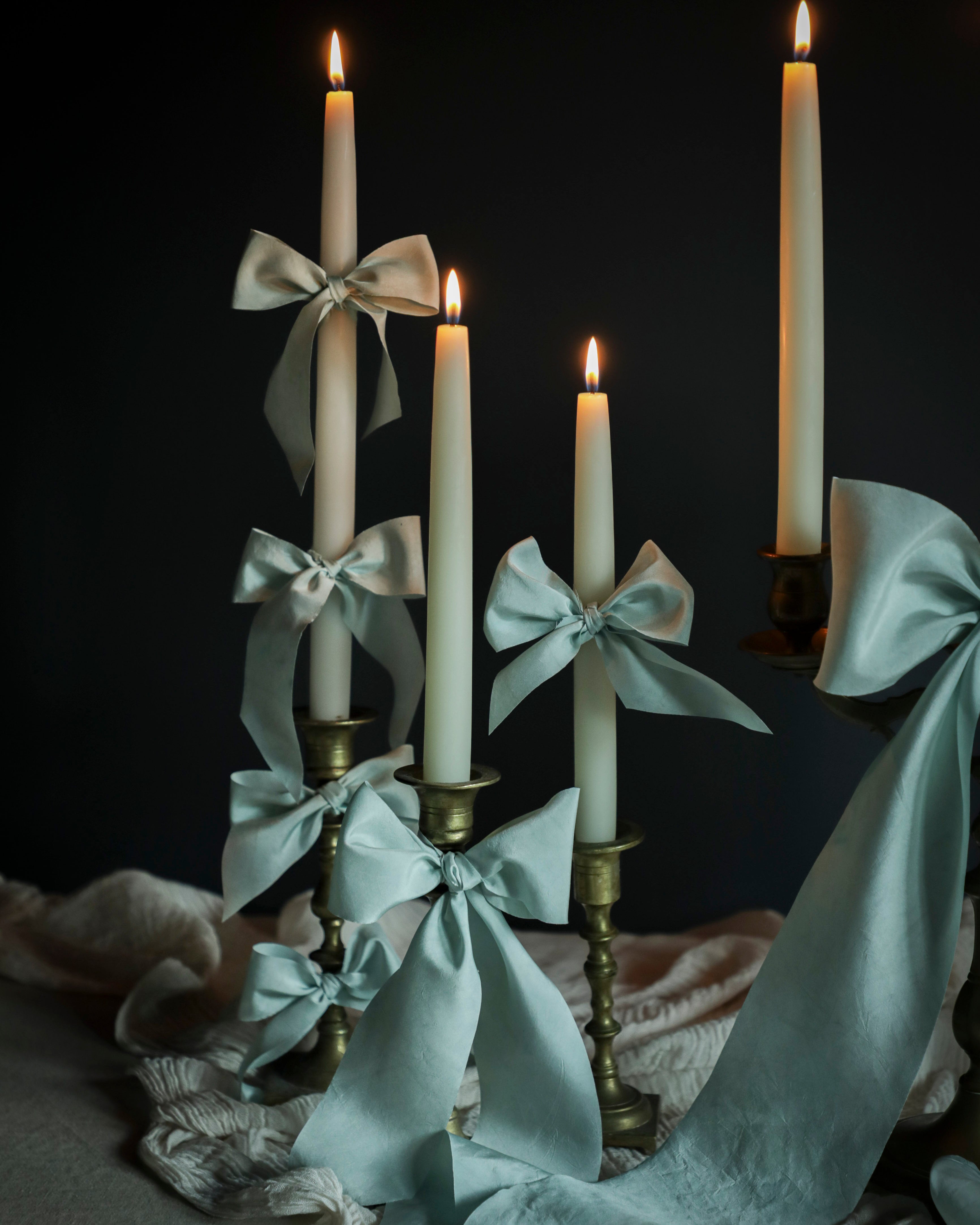 Candlesticks with light blue ribbons and candles against a dark background