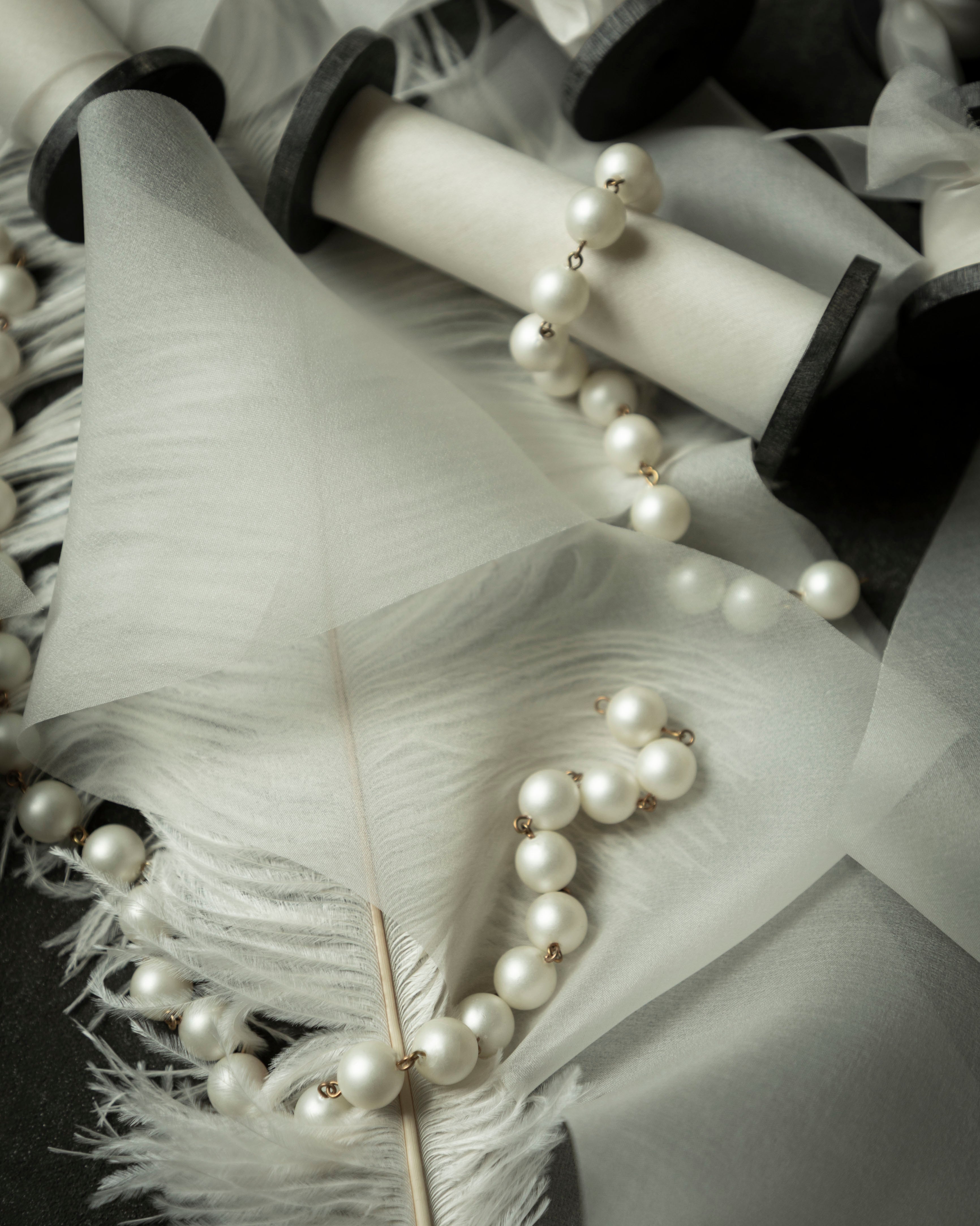 antique white wedding ribbon for florists. Displayed on a flatlay with white feather and pearls.