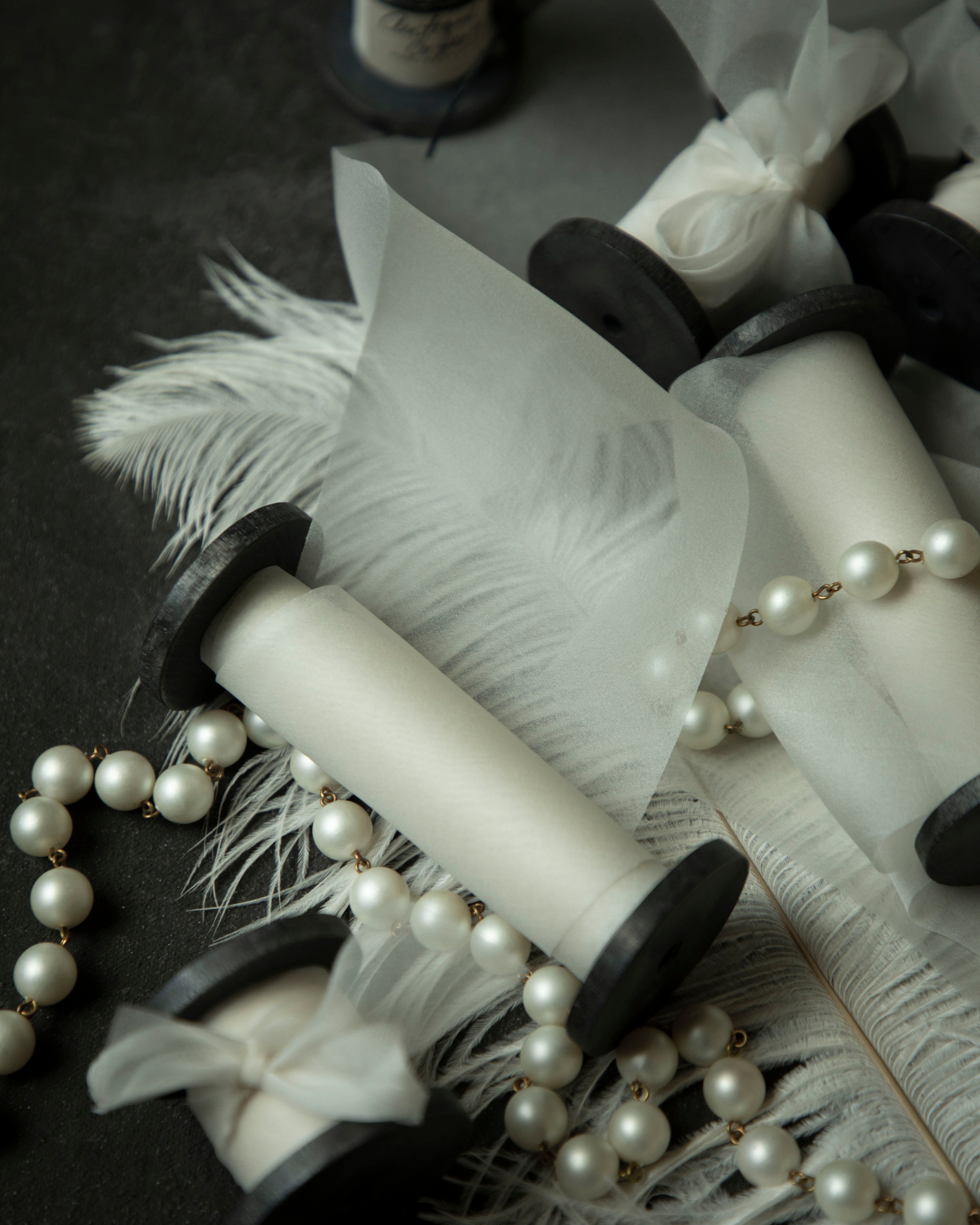 close-up of antique white wedding ribbon for florists. Displayed on a flatlay with white feather and pearls.