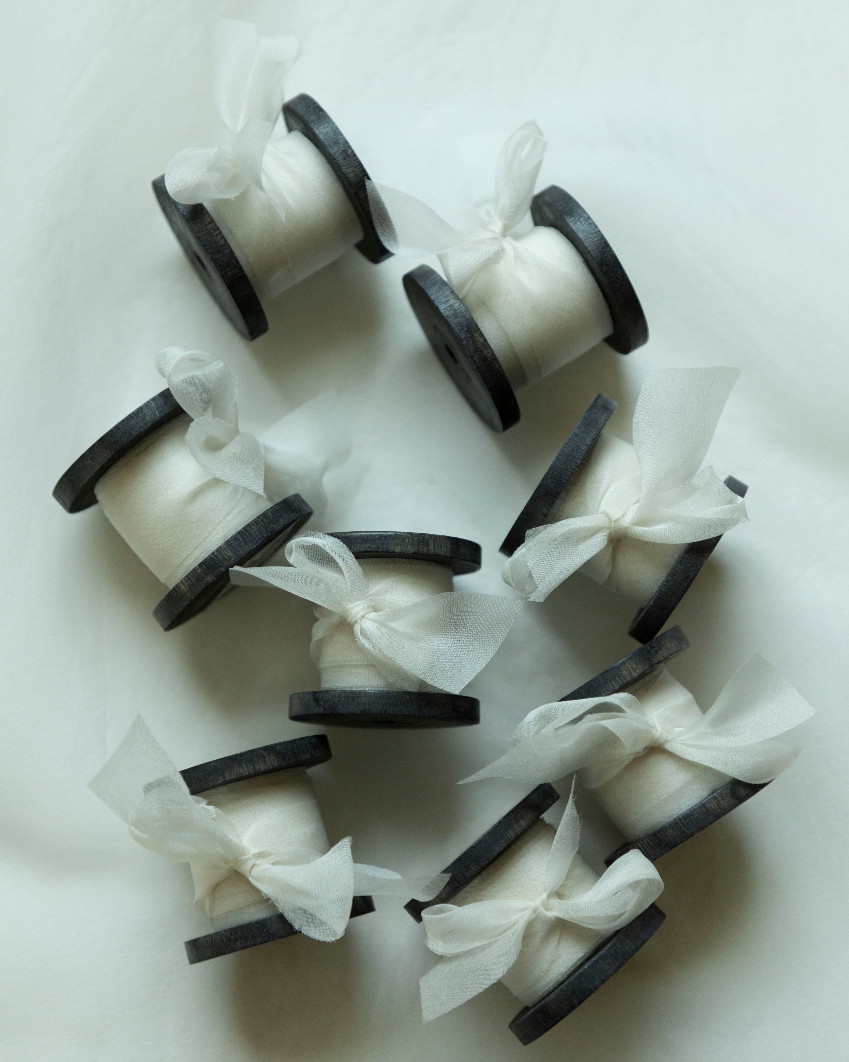 antique white organza silk ribbon on antique wood spool, displayed on white background