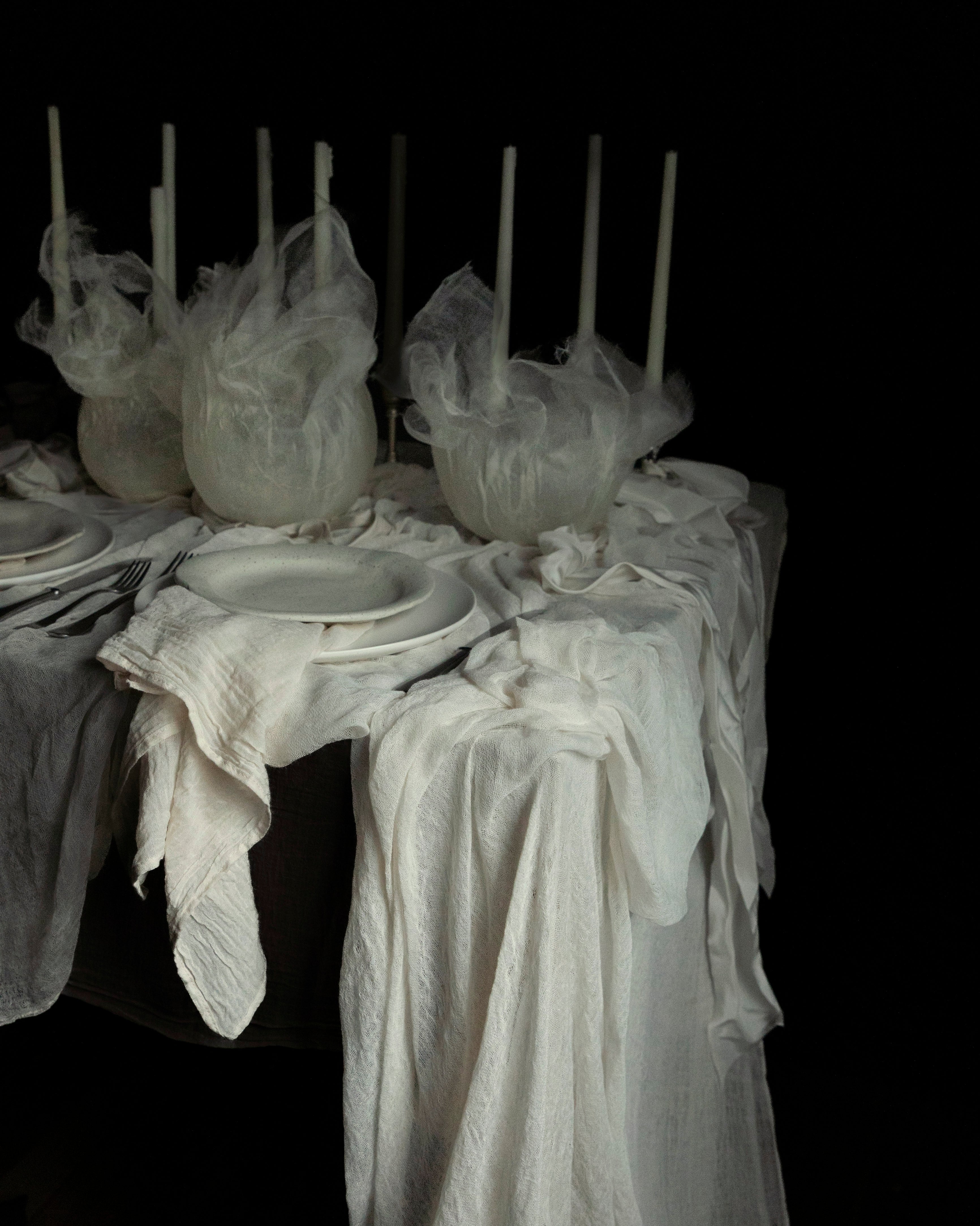 Antique white hand-loomed plant-dyed cotton table runner draped elegantly across a table, showcasing its unique textures and natural hues, ideal for creating a bespoke tablescape design.