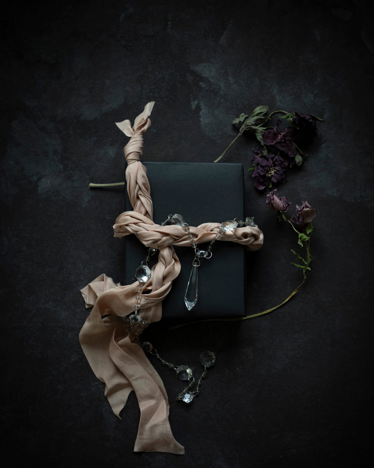 Dark box with blush ribbon and decorative elements on a dark background