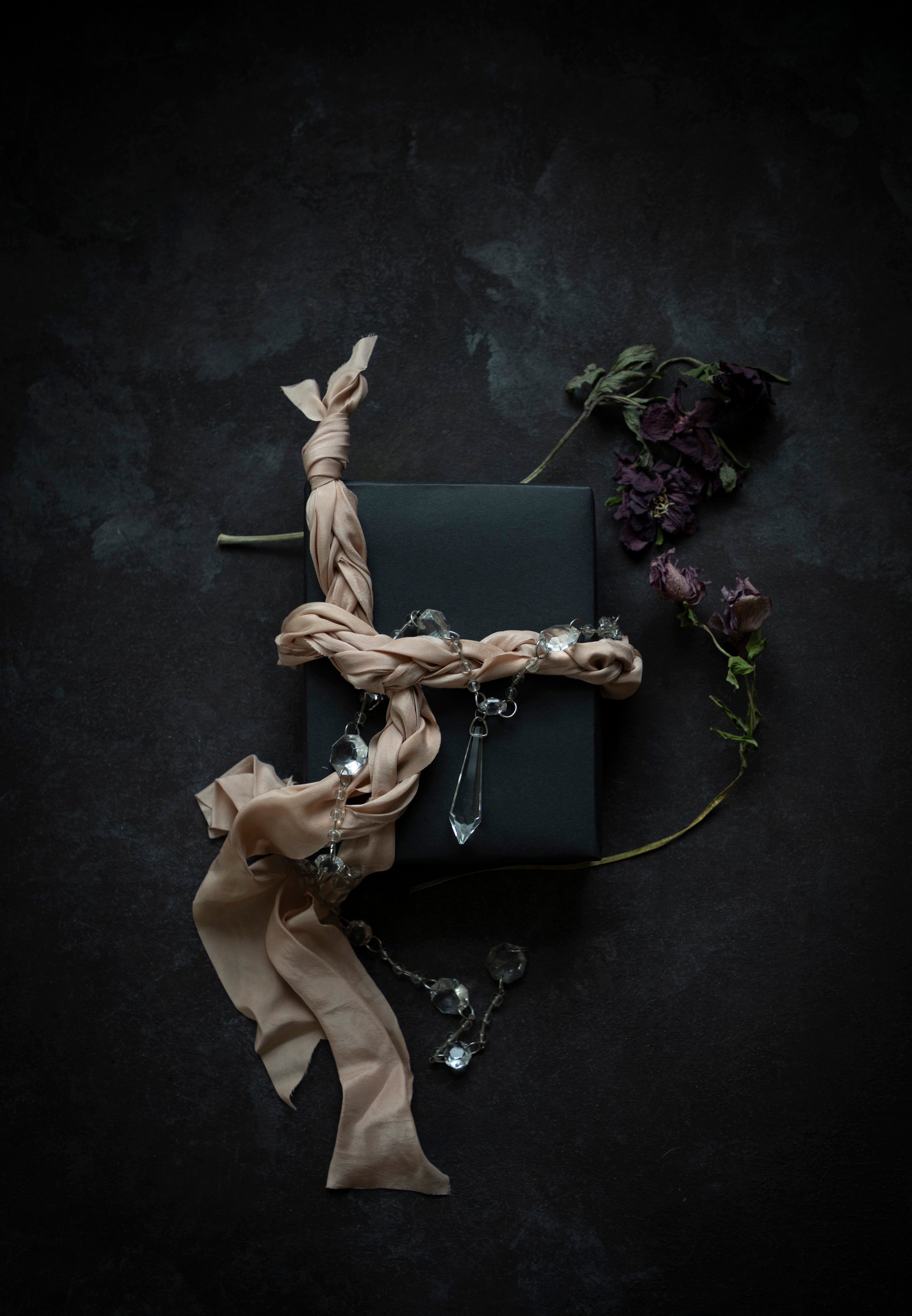Dark box with blush ribbon and decorative elements on a dark background