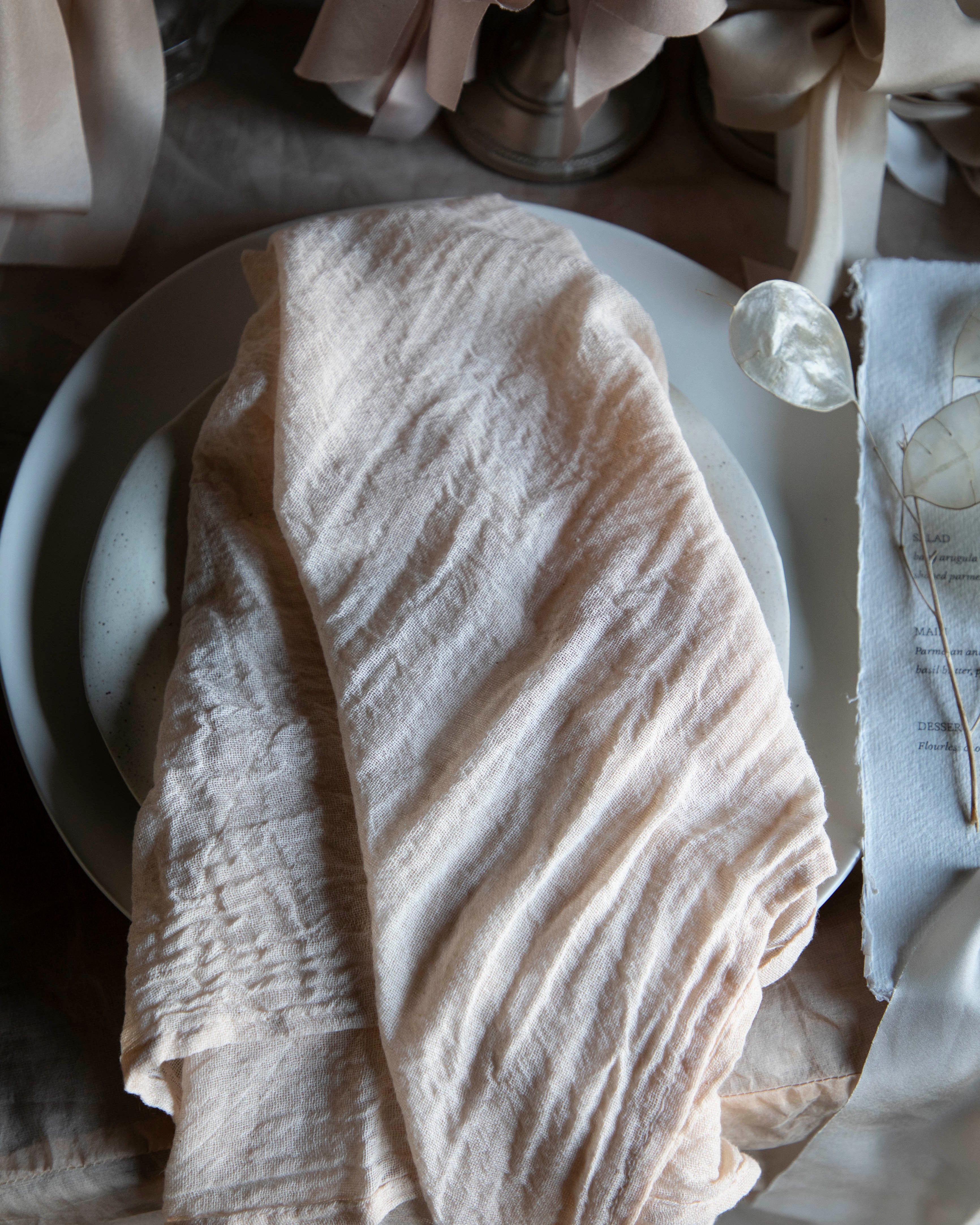 Neatly folded beige napkin on a white plate with a blurred background