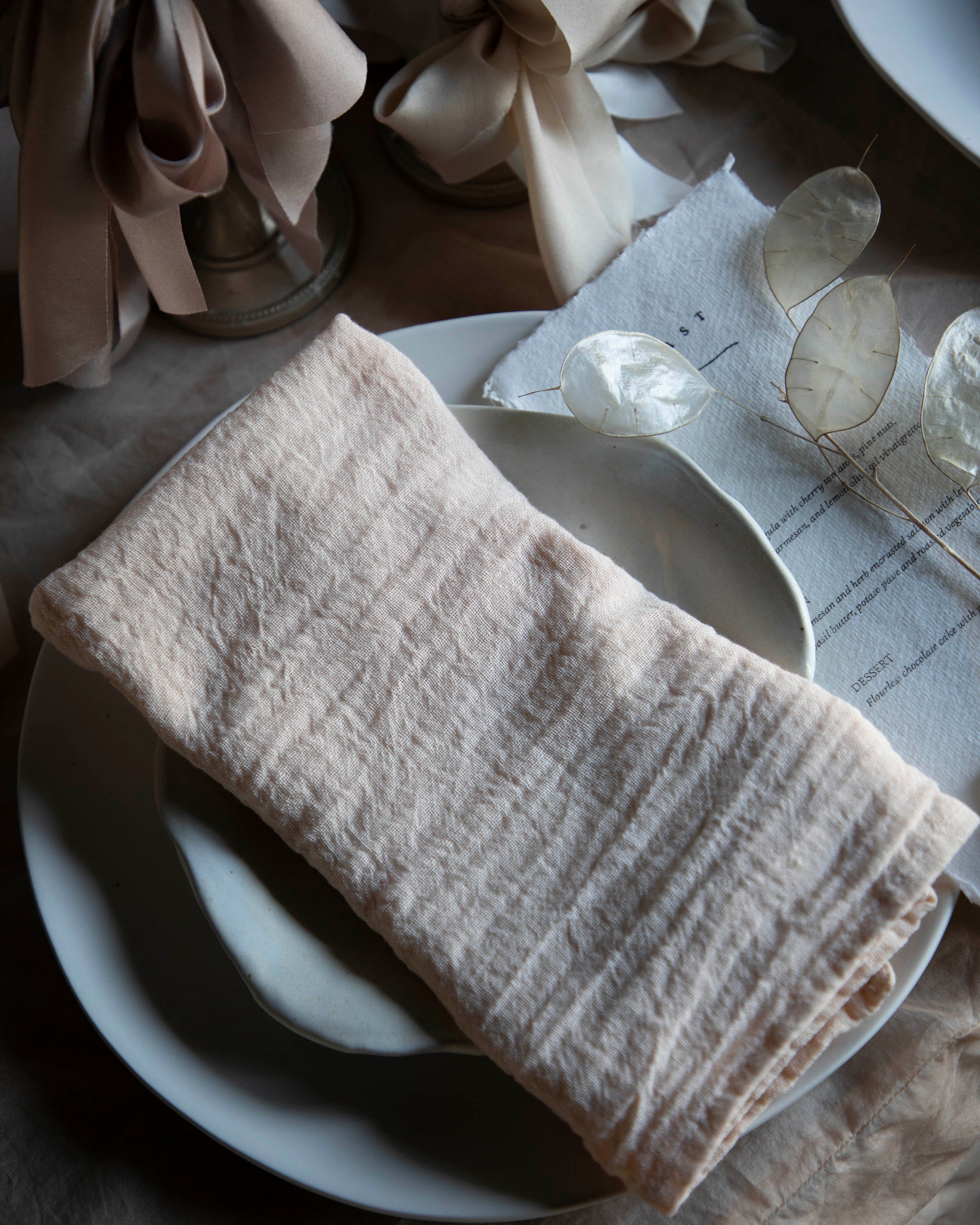 Folded blush napkin on a white plate with a textured surface