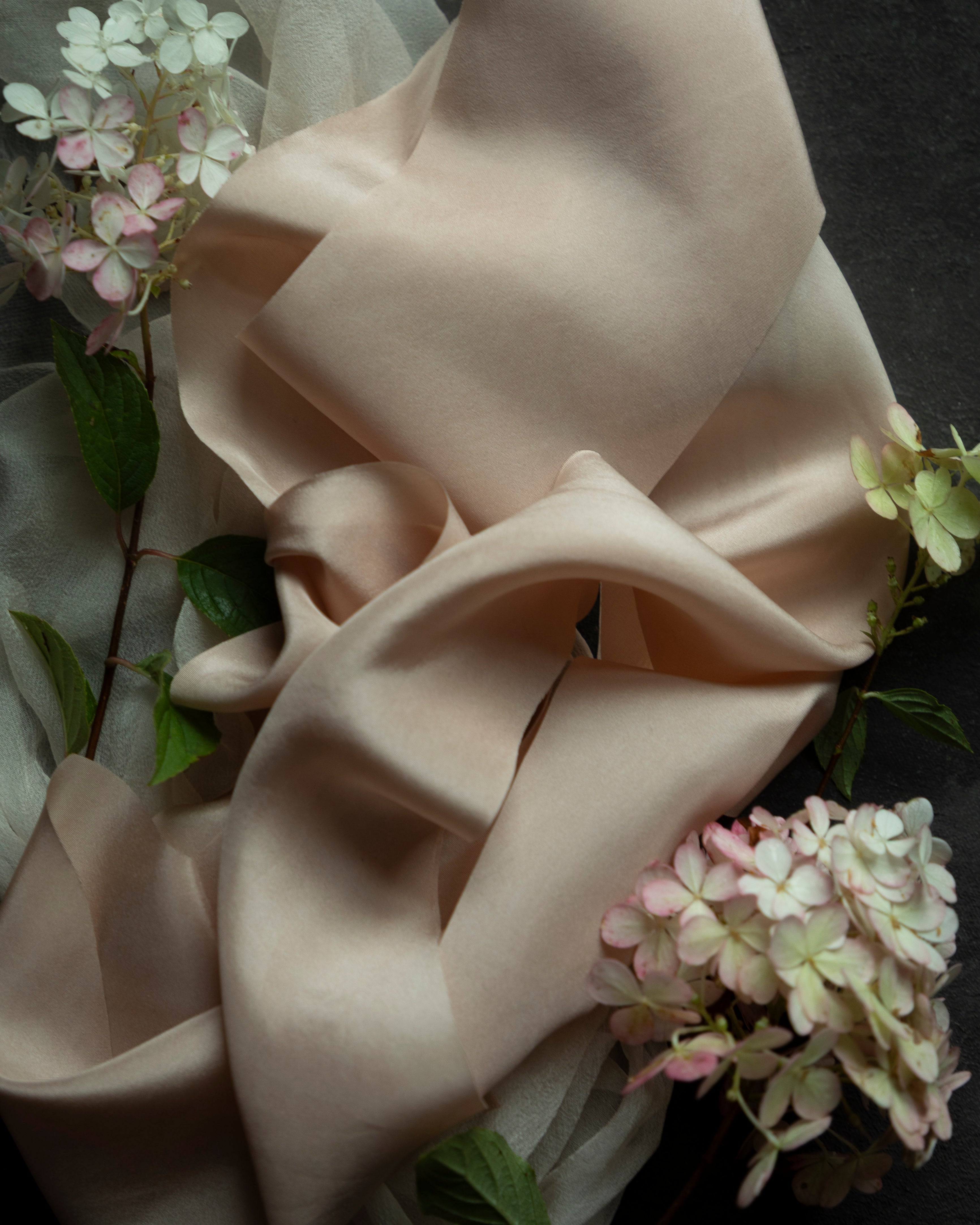 blush ribbon and fabric with floral elements on a dark background