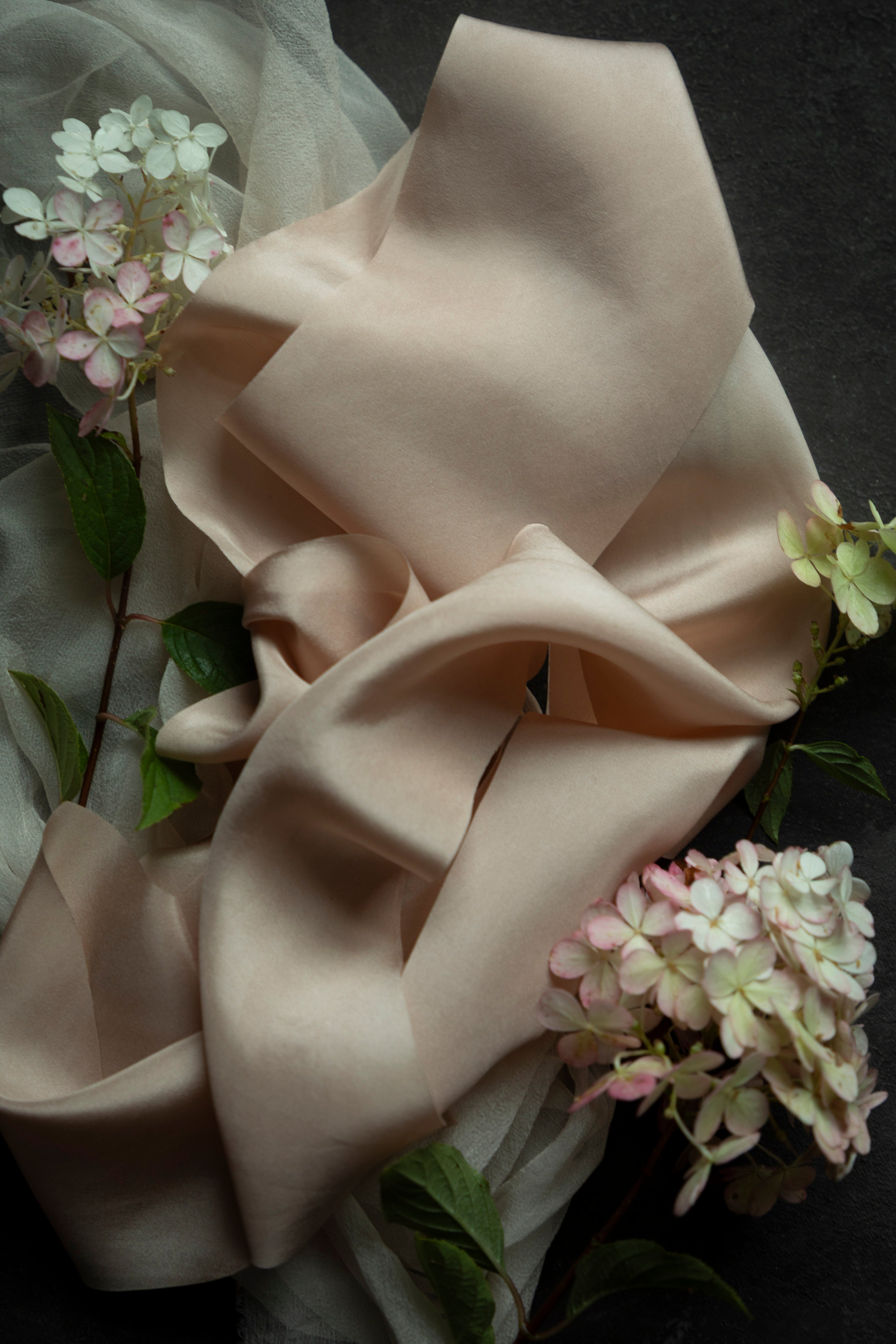 blush ribbon and fabric with floral elements on a dark background