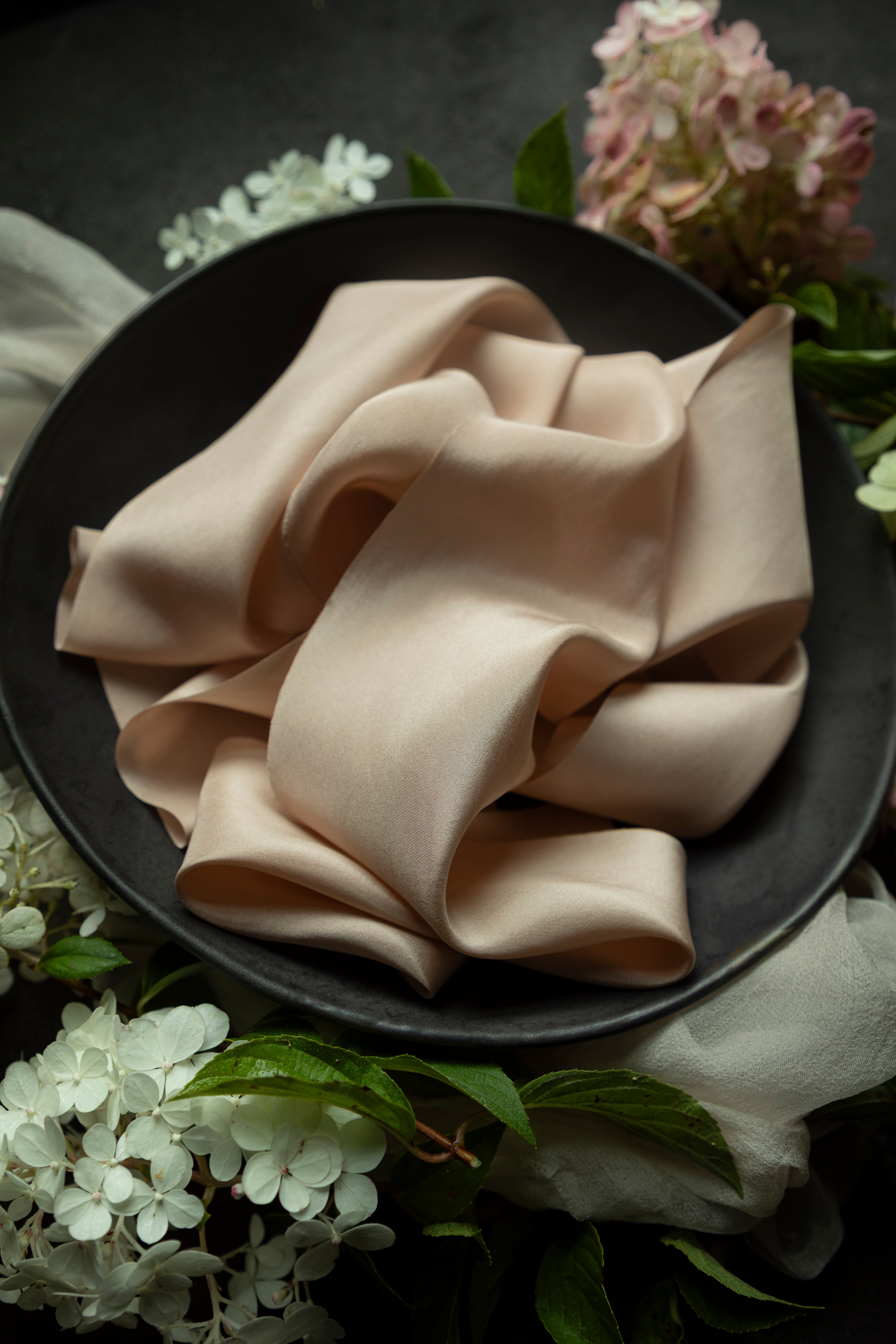 Folded blush ribbon on a dark plate with floral decorations
